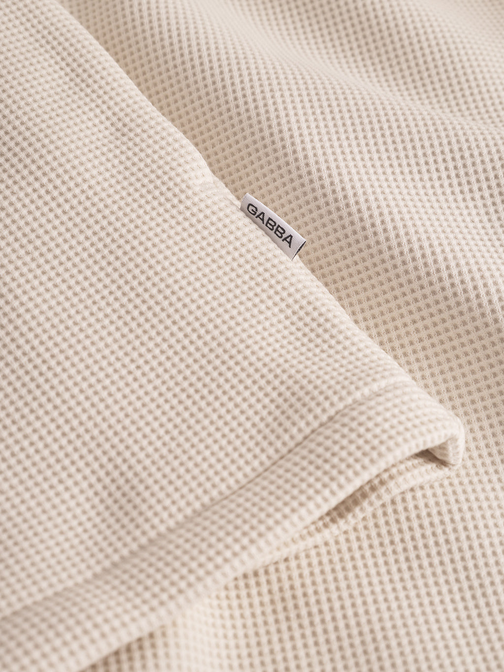 Close-up of the Gabba Como Waff overshirt in White Almond, showcasing its soft waffle texture, minimalist silhouette, and a discreet white Gabba tag sewn into the seam.