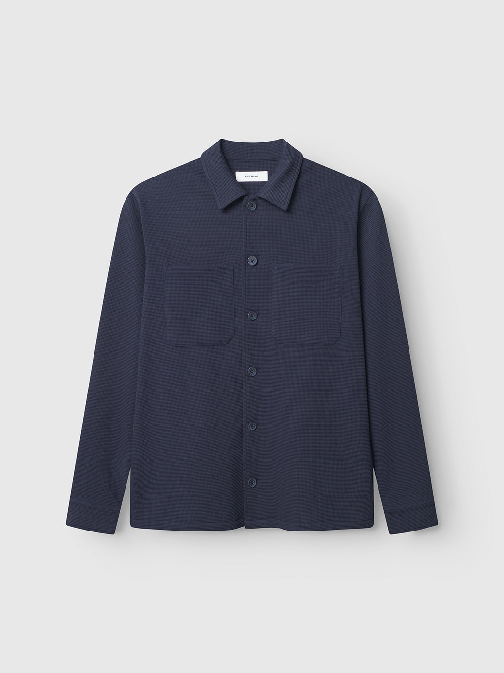 The Gabba Como Waff - Navy is a long-sleeve overshirt with a collar, button-down front, and two chest pockets, made from recycled cotton. Shown against a plain white background.
