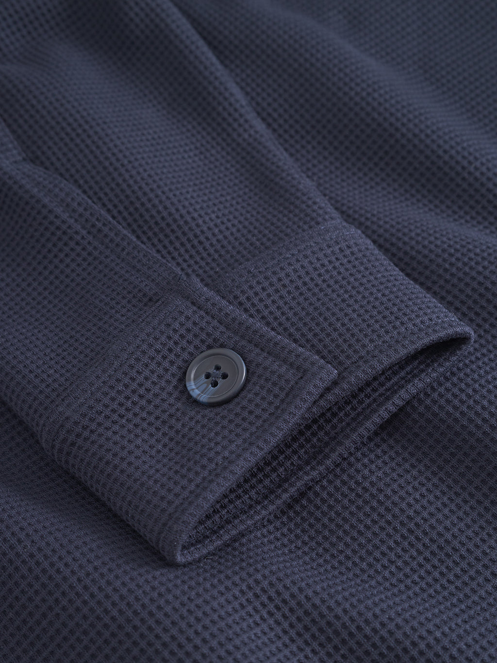 Close-up of the Gabba Como Waff - Navy overshirt sleeve, featuring a textured waffle knit and grid-like pattern, with a black button on the dark navy cuff.