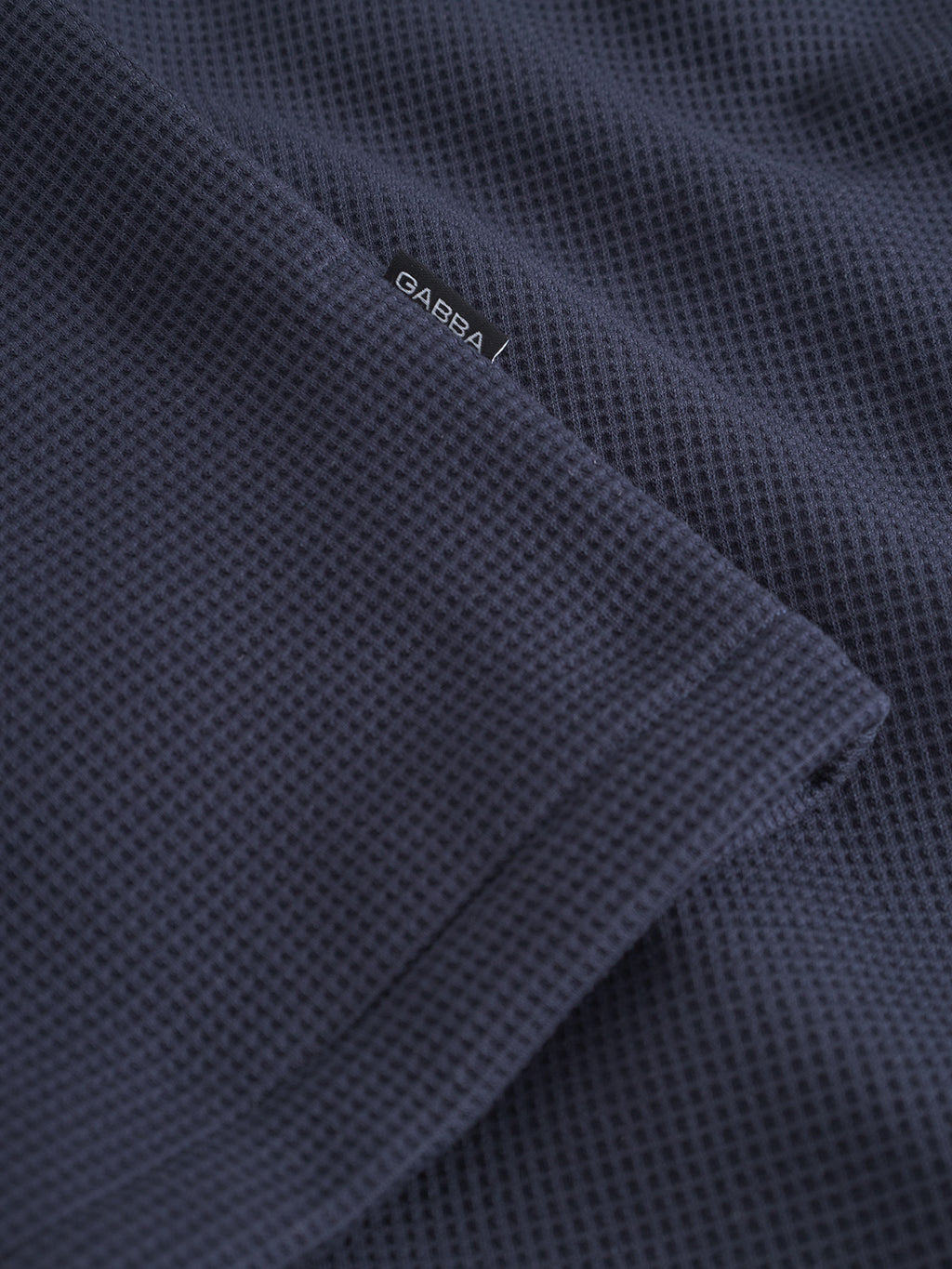Close-up of the Como Waff - Navy fabric by Gabba, a dark blue waffle knit often used for overshirts, featuring a small sewn-on Gabba label.