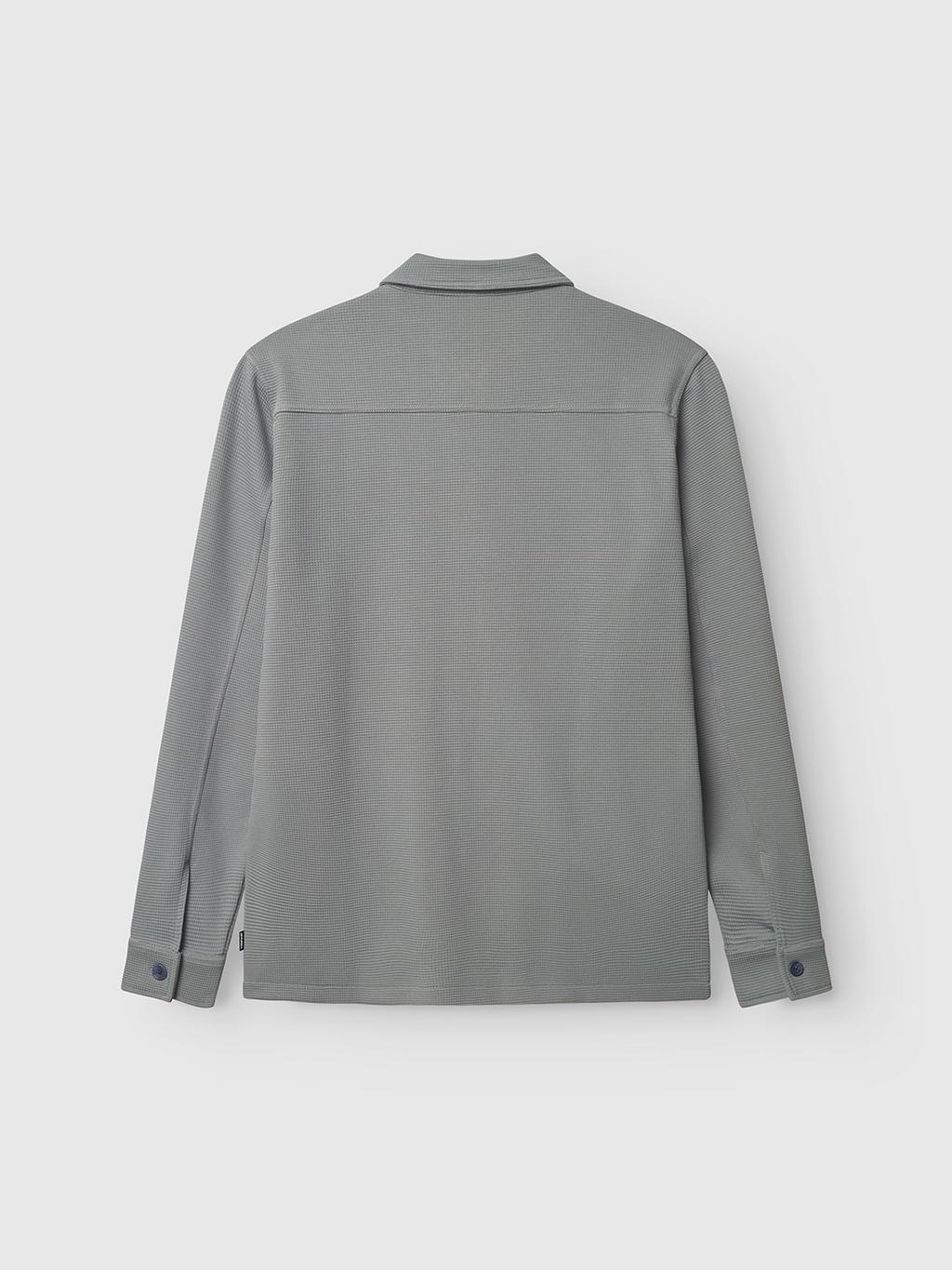 The Gabba Como Waff in Dust Sage Green is a long-sleeved collared shirt, shown flat from the back with buttoned cuffs and a straight hem—an ideal layering piece—set against a plain white background.