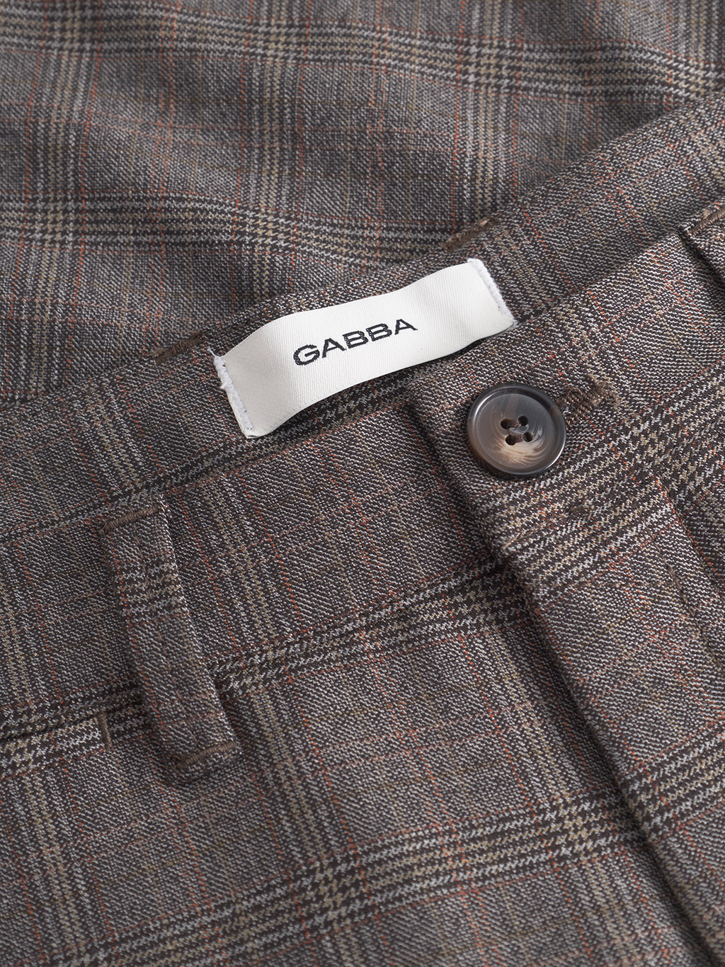 Close-up of Gabbas Paul Tinun - Brown Check pants in plaid, with a black button and white GABBA label inside the waistband. Designed for stretch comfort in a slim straight silhouette.