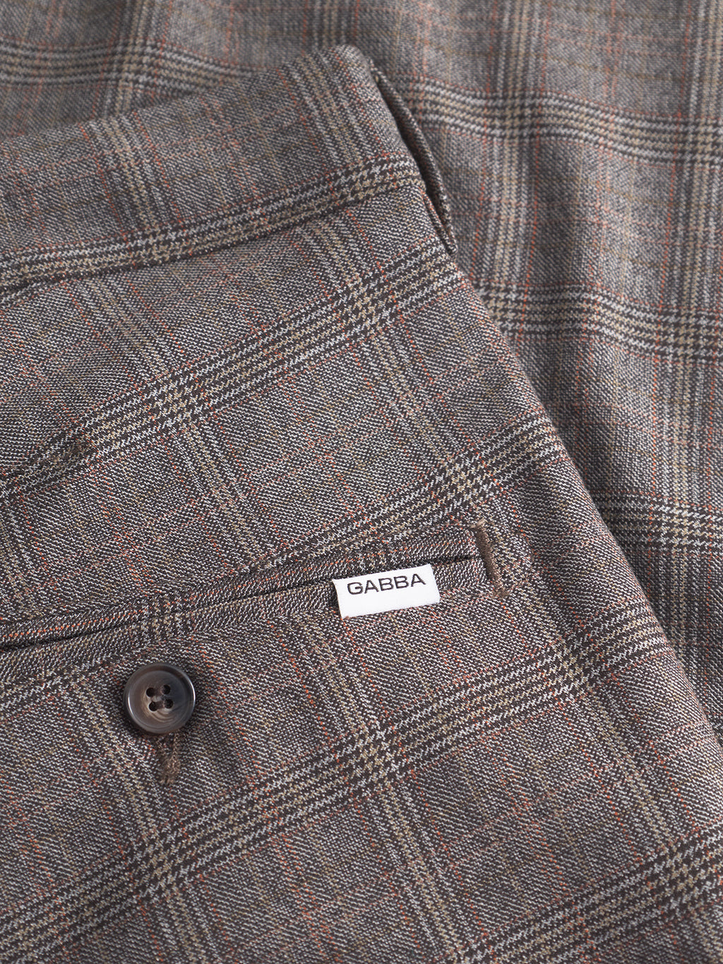Close-up of Gabba’s Paul Tinun - Brown Check: gray plaid slim straight pants with brown and red lines, featuring a back pocket with a brown button and a small white Gabba label, designed for stretch comfort.