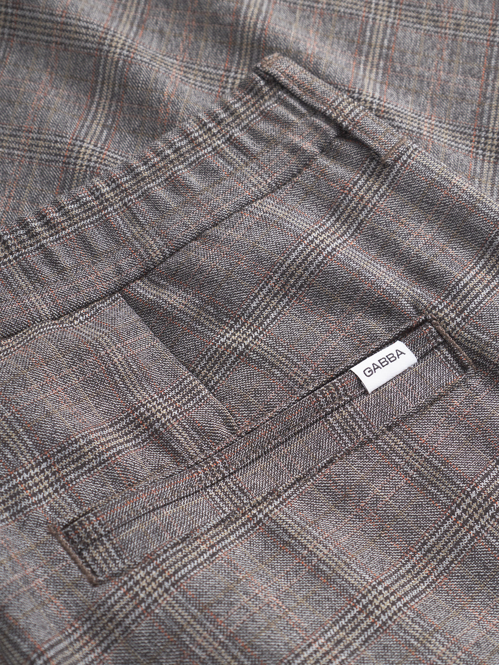 Close-up of Gabba Monza Tinun - Brown Check pants in a regular straight fit, with a back pocket and white label. Features gray fabric with subtle brown check lines, crafted from bi-stretch comfort material for ease and style.