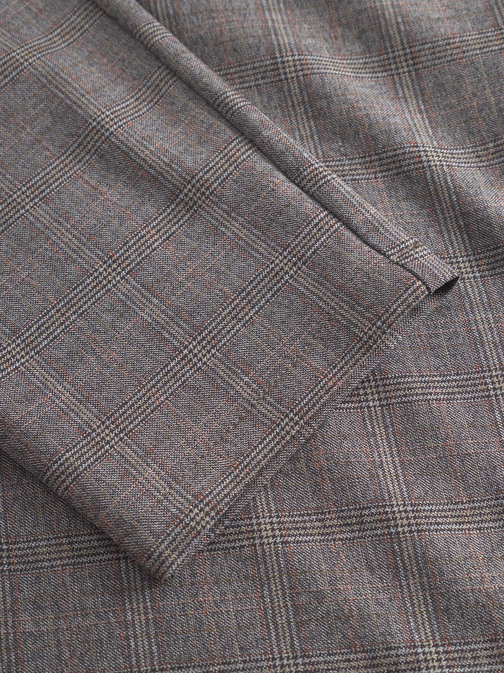 Close-up of Gabba Monza Tinun - Brown Check, a folded grey bi-stretch comfort fabric with a smooth, wool-like texture and a plaid pattern featuring thin intersecting brown and black lines.