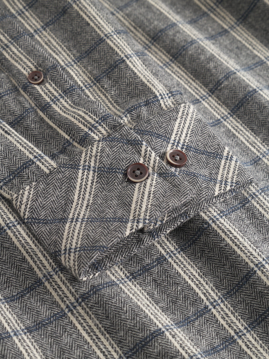 Close-up of the Sven Reg Herri LS shirt by Gabba in grey, showing the detailed fabric texture, check pattern, and buttoned cuff with brown buttons.