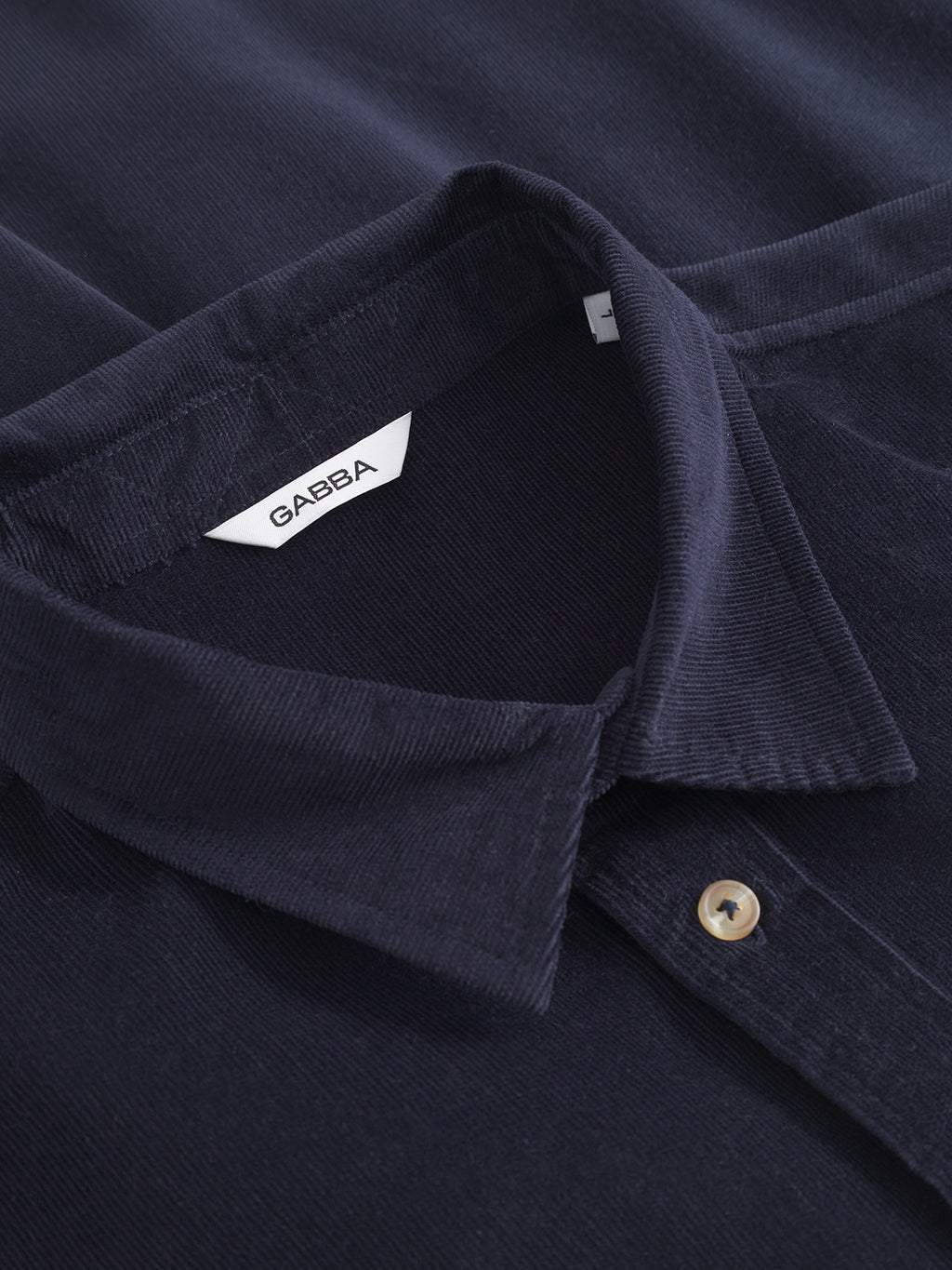 Close-up of the Gabba Jens Over Cord LS - Night Sky: a navy blue corduroy overshirt with a folded collar, visible button, and inner white Gabba label—perfect for versatile layering.