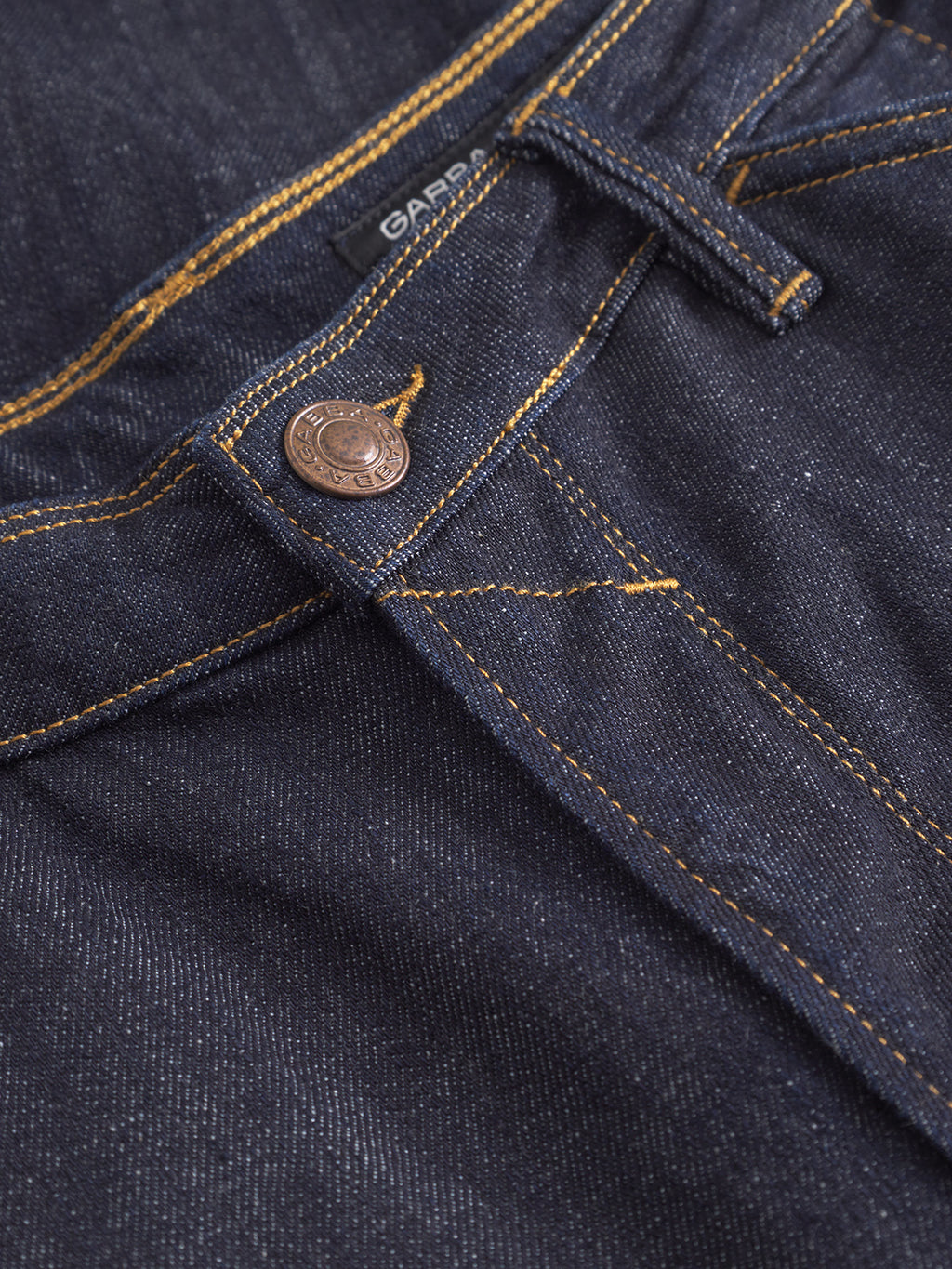 Close-up of Gabbas Max Work Self dark blue denim jeans with yellow stitching, a metal button, belt loop, and a partially visible black label.