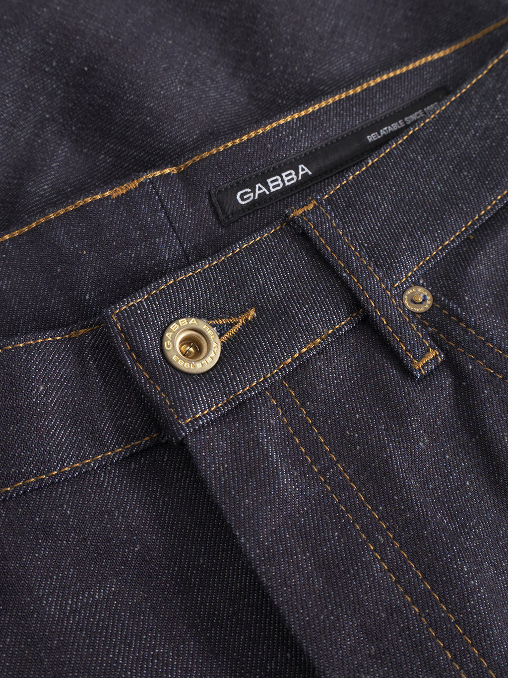 Close-up of the waistband and metal button on Marc Tana - Dark Blue Denim jeans by Gabba, featuring orange stitching and a black label with the Gabba brand name sewn inside.