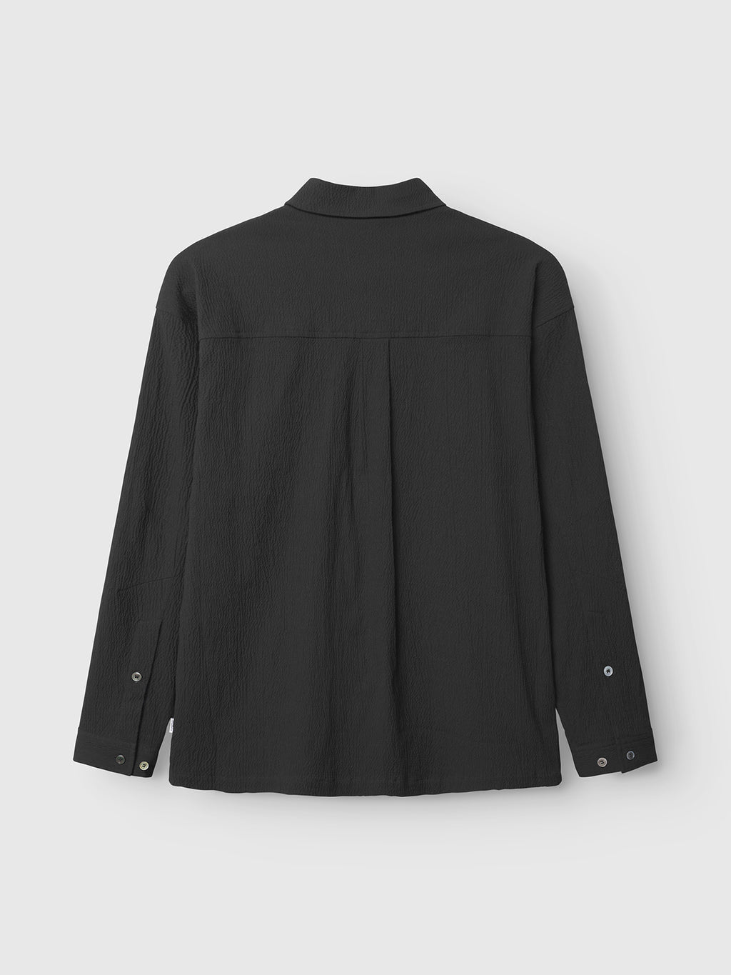 The Gabba Jens Over Siro LS GOTS - Black is a wrinkle-free button-up shirt with a classic collar, buttoned cuffs, and straight hem, shown laid flat from the back for timeless style and easy care.