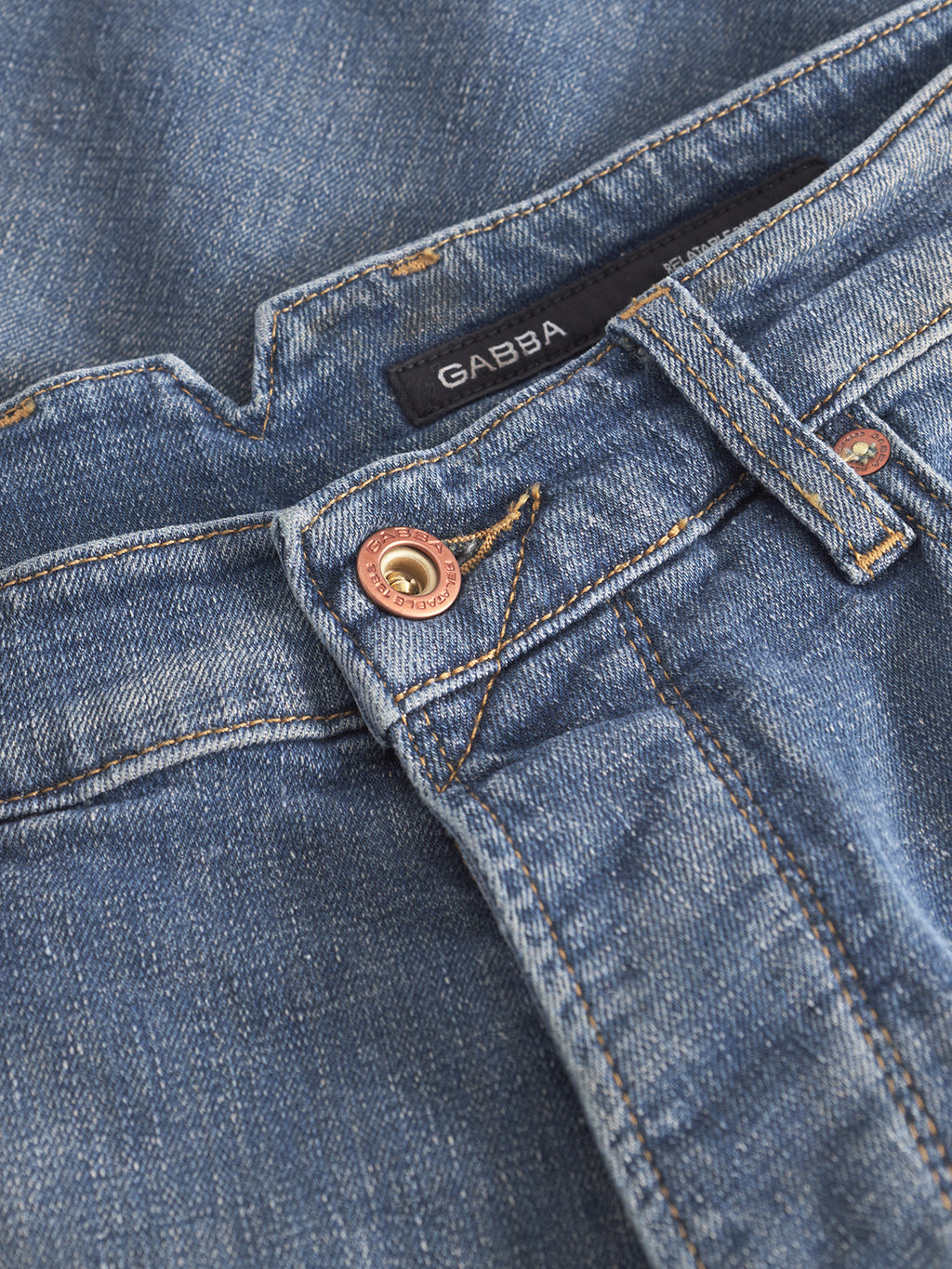 Close-up of Gabba Alex Ulio - Mid Blue Denim relaxed tapered jeans featuring visible stitching, a copper button, stretch comfort, and a black Gabba label near the waistband.