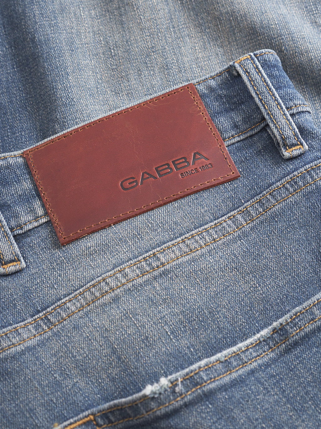 Close-up of Gabba’s Alex Ulio - Mid Blue Denim relaxed tapered jeans, featuring a brown leather patch with GABBA and SINCE 1983 embossed above the back pocket, designed for stretch comfort.
