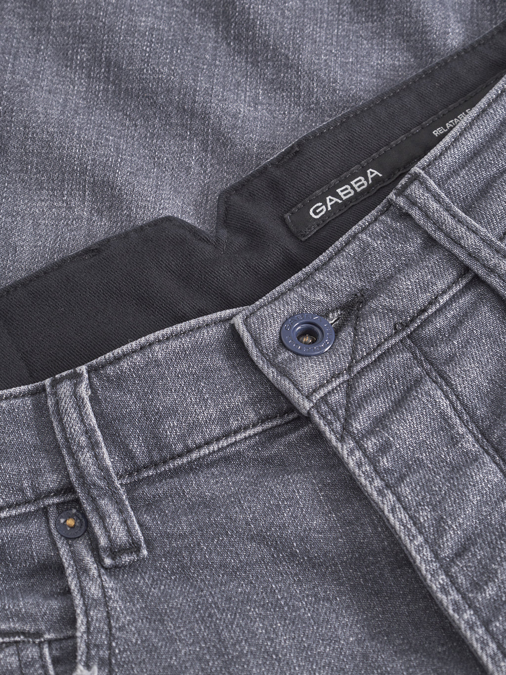 Close-up of the waistband and button on the Alex Sotto - Grey Denim jeans by Gabba. Made from stretch cotton, these relaxed tapered jeans feature visible stitching, a navy button, and an inner Gabba label.