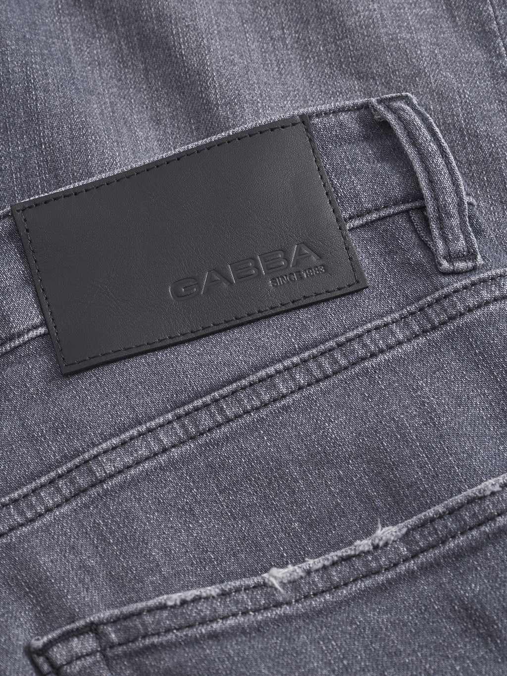 Close-up of the back pocket of Alex Sotto - Grey Denim jeans by Gabba, with a black leather patch embossed with Gabba and Since 1983. Made from premium stretch cotton for all-day comfort.