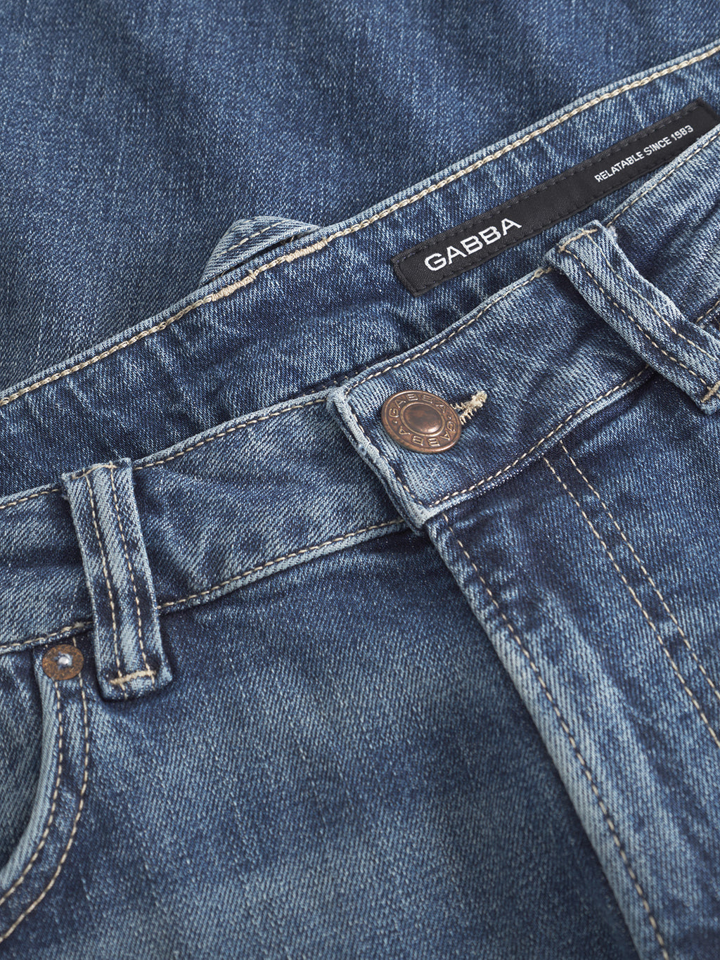 Close-up of Gabba Carl Jingo dark blue denim stretch jeans featuring visible stitching, a metal button, and a black waistband label with “GABBA” and “DELIVERING SINCE 1983.”.