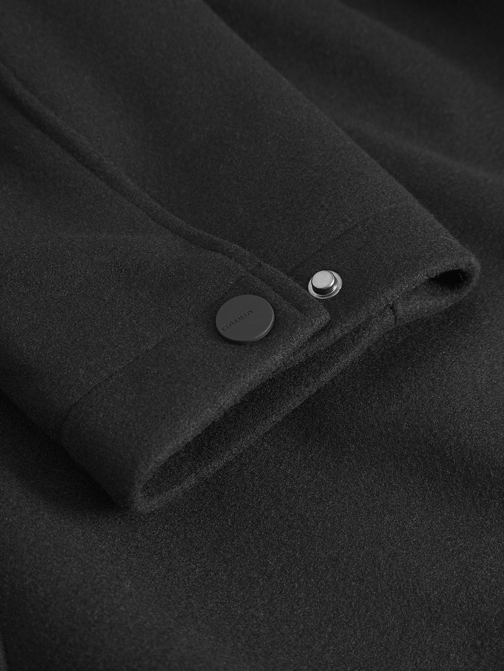 Close-up of the Gabba Orta Wox - Black sleeve, featuring a matte black button and glossy metallic snap on the windproof performance fabric.