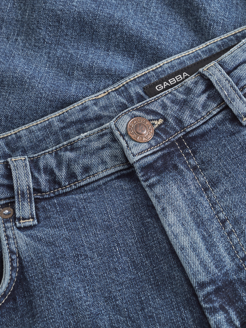 Close-up of Gabba’s Marc Jingo dark blue denim jeans featuring a copper JEANS-engraved button, belt loops, black label, and comfort stretch. Expertly crafted in a straight-leg style for easy wear.