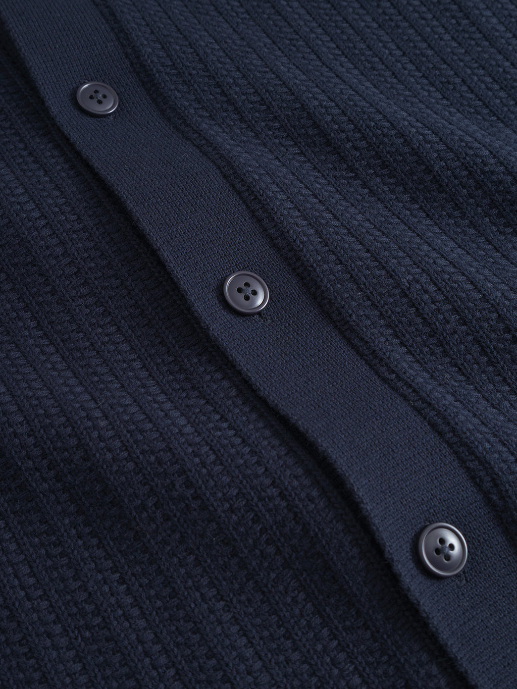 Close-up of the Sakai Wong LS by Gabba: a navy ribbed cotton knit with four dark buttons along a placket, showing the tops soft texture and patterned design.