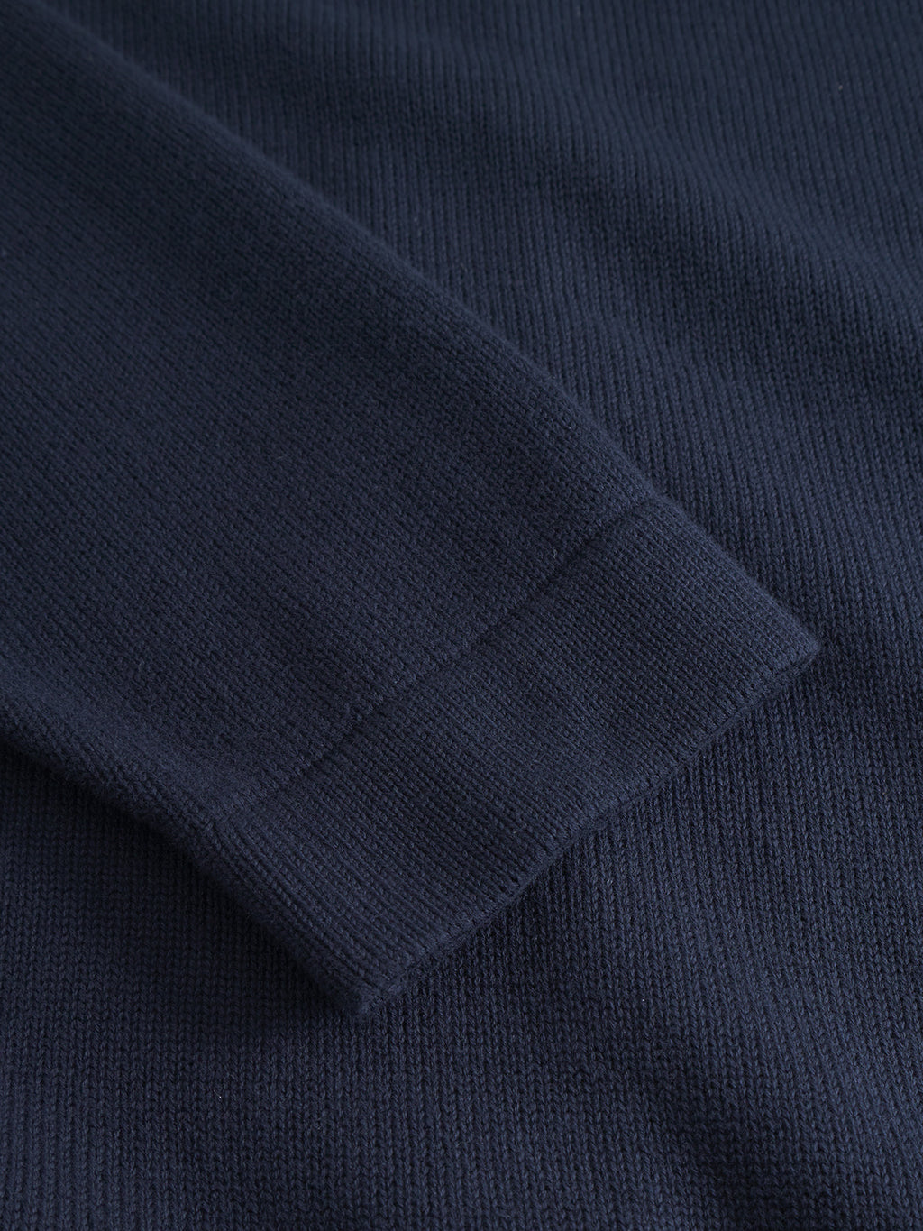 A close-up of the Gabba Sakai Wong LS sweater in navy, highlighting its cotton knit fabric and finely ribbed sleeve cuff.