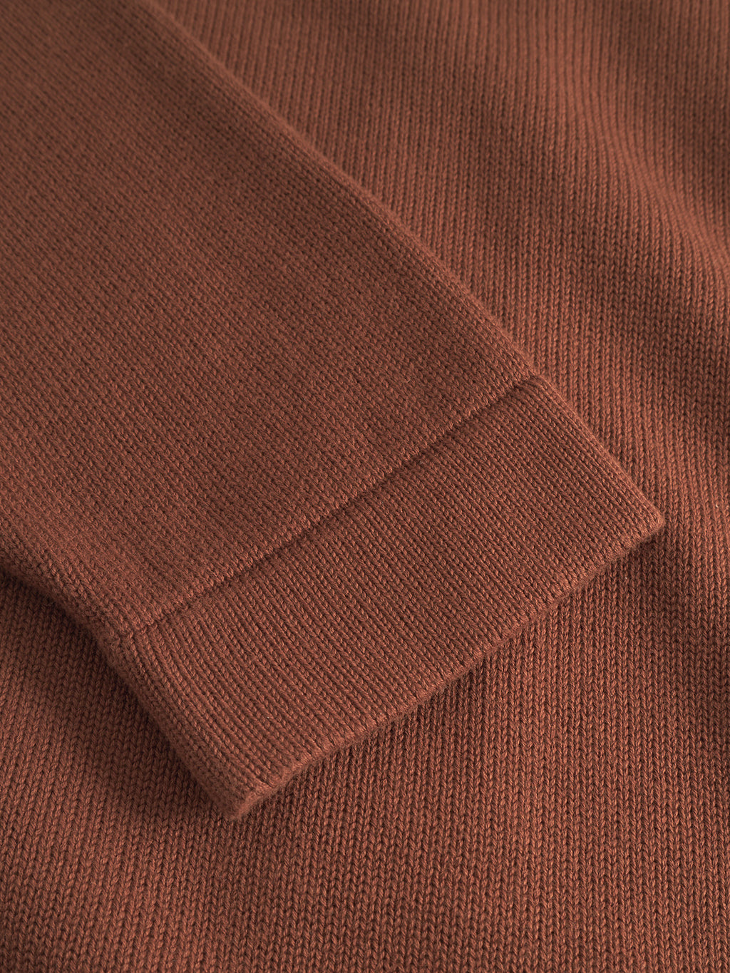 Close-up of the Gabba Sakai Wong LS cardigan sleeve in brown rust, lying flat and showcasing the cotton fabric’s texture and ribbed cuff.