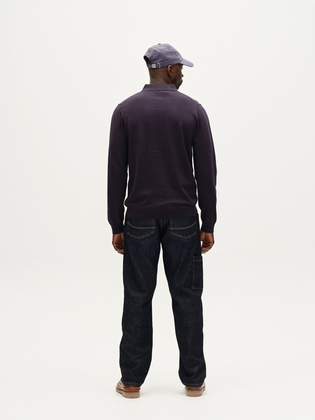 A man faces away from the camera, wearing the Gabba Akita Prex LS - Navy long-sleeve shirt, dark jeans, brown shoes, and a navy cap, all set against a plain white background.