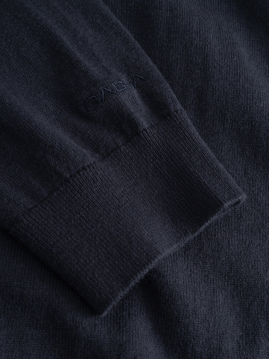 Close-up of the Gabba Akita Prex LS in navy—a dark knit sweater with a ribbed cuff and subtle Gabba branding near the wrist, ideal for layering under a navy polo and a must-have modern wardrobe essential.