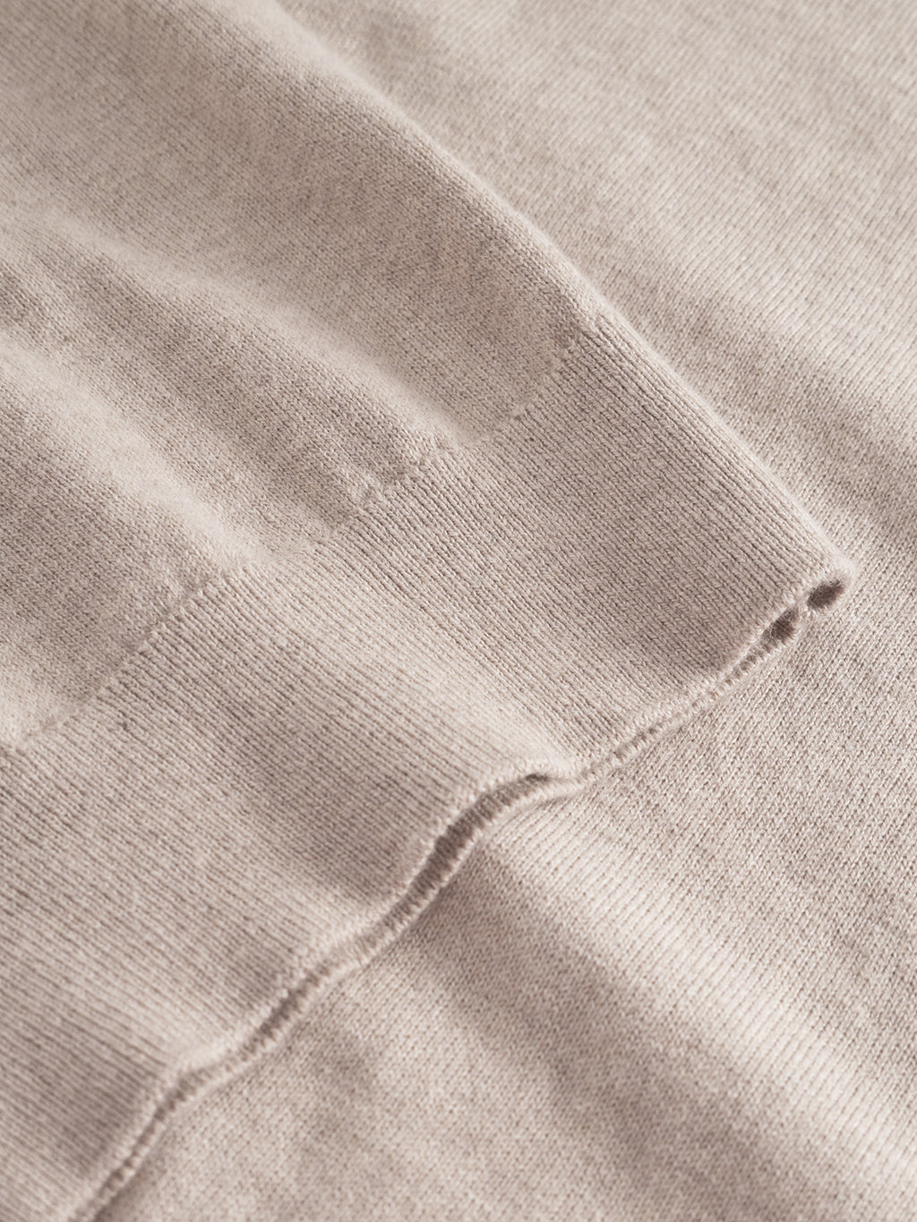 Close-up of the Akita Prex LS - Sand by Gabba shows its soft, light beige knit and visible seam, emphasizing the refined comfort and premium quality characteristic of this cozy long-sleeve polo.