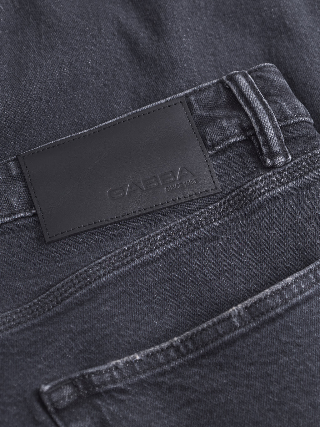 Close-up of Carl Puma - Black Denim relaxed fit jeans featuring a black leather patch embossed with Gabba and SINCE 1983 above the back pocket.
