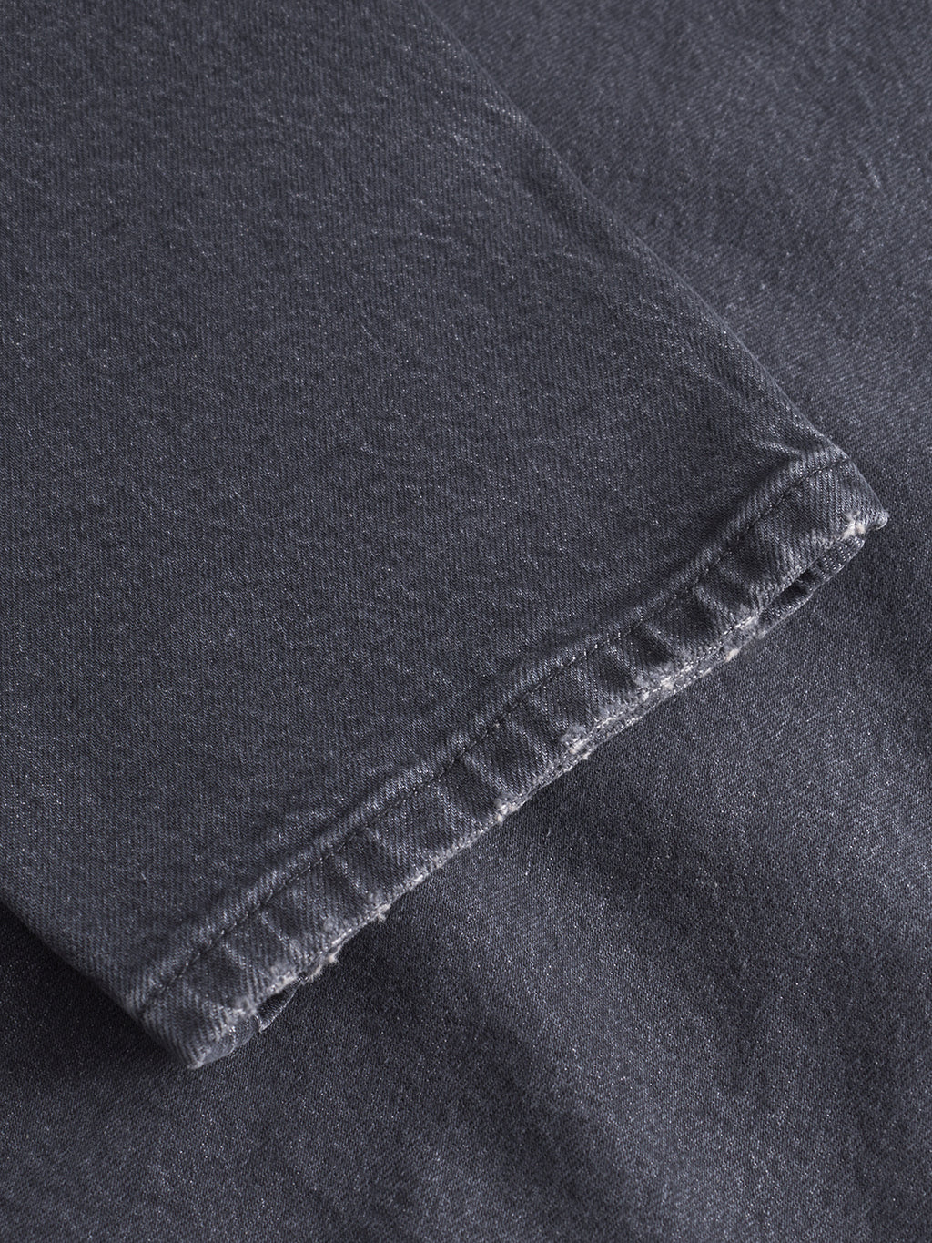 Close-up of Gabbas Carl Puma - Black Denim, highlighting the hem with visible stitches and slightly frayed threads. The texture and weave of the black denim fabric are clearly shown.