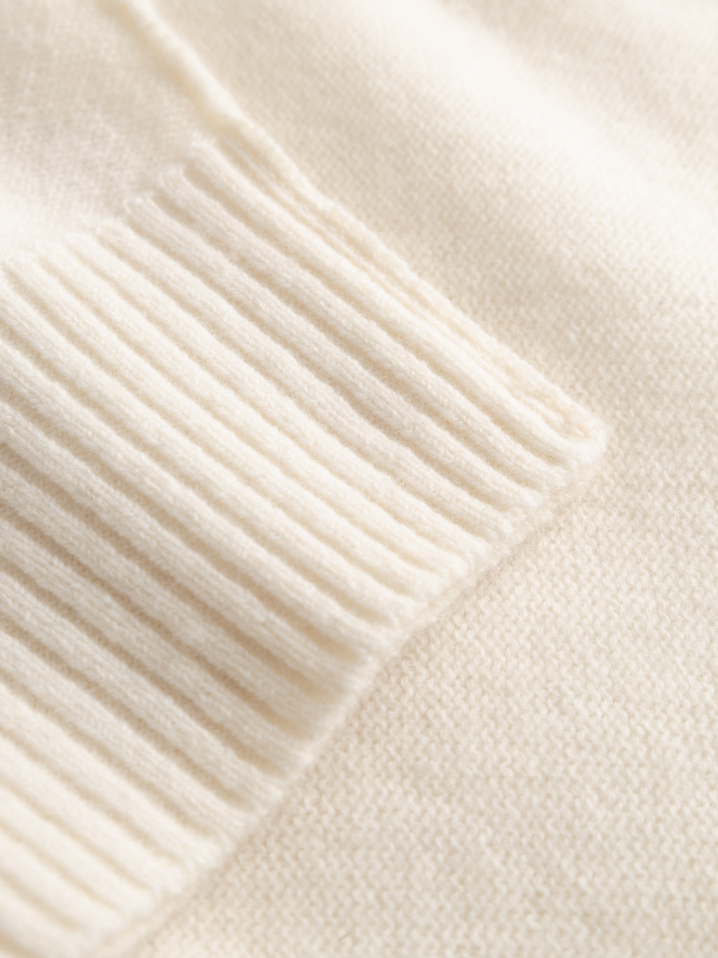 Close-up of the Gabba Tokota Aico LS in off white, showing a ribbed cuff on a smooth, finely knit surface. The contrast in textures makes this wool sweater a cozy and stylish layering piece.