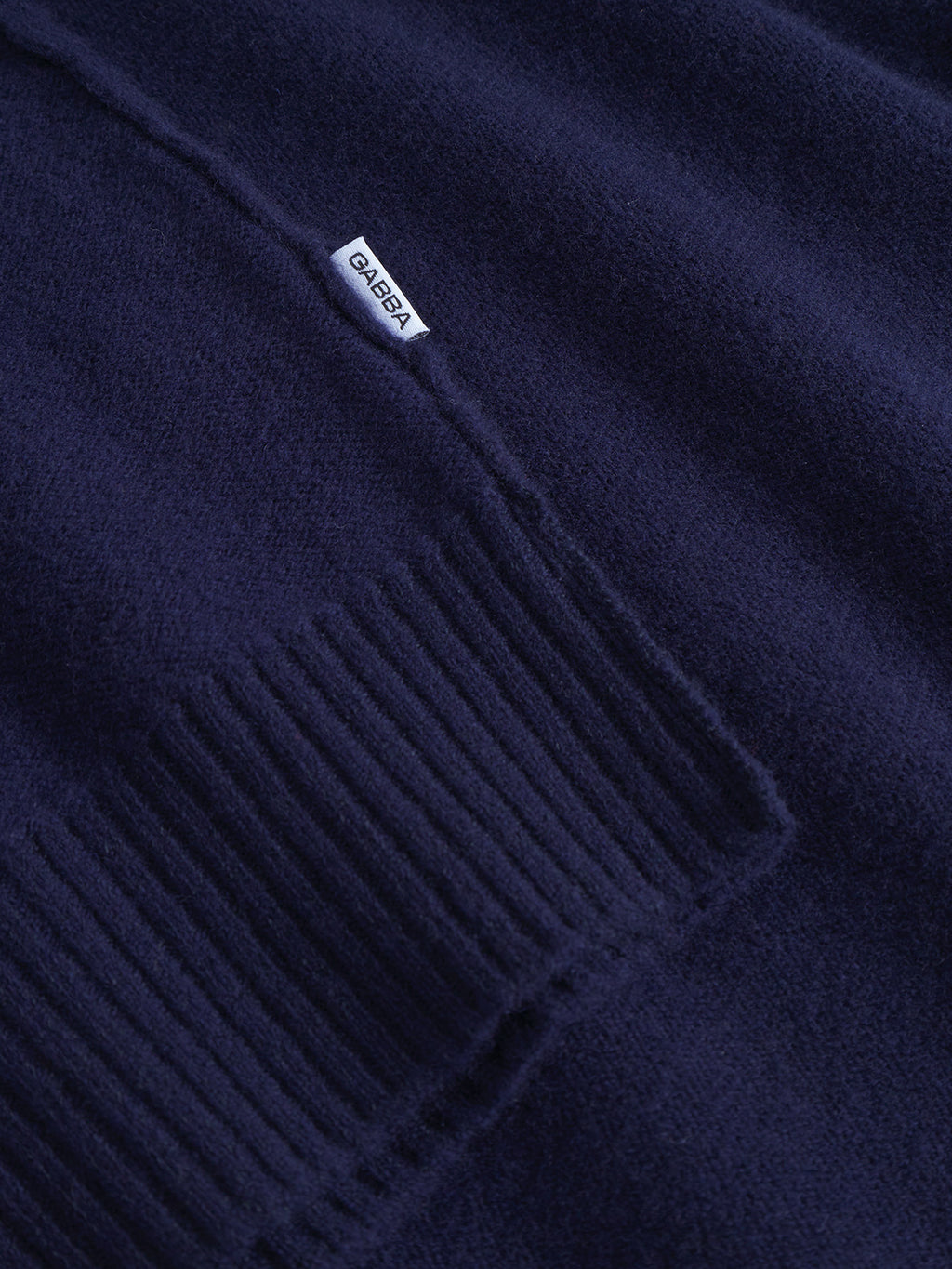 Close-up of the Tokota Aico LS in Dark Navy by Gabba, showcasing ribbed knit fabric and a small white rectangular Gabba label sewn onto it.