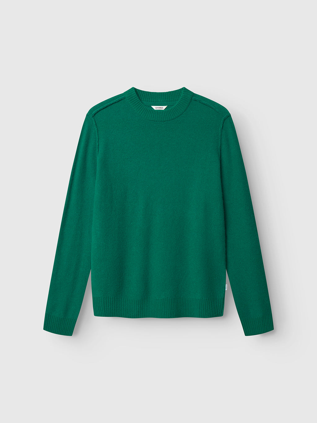 The Gabba Tokota Aico LS - Green, a plain long-sleeved crew-neck merino sweater, is laid flat on a light gray background, highlighting its luxurious pure merino wool fabric.