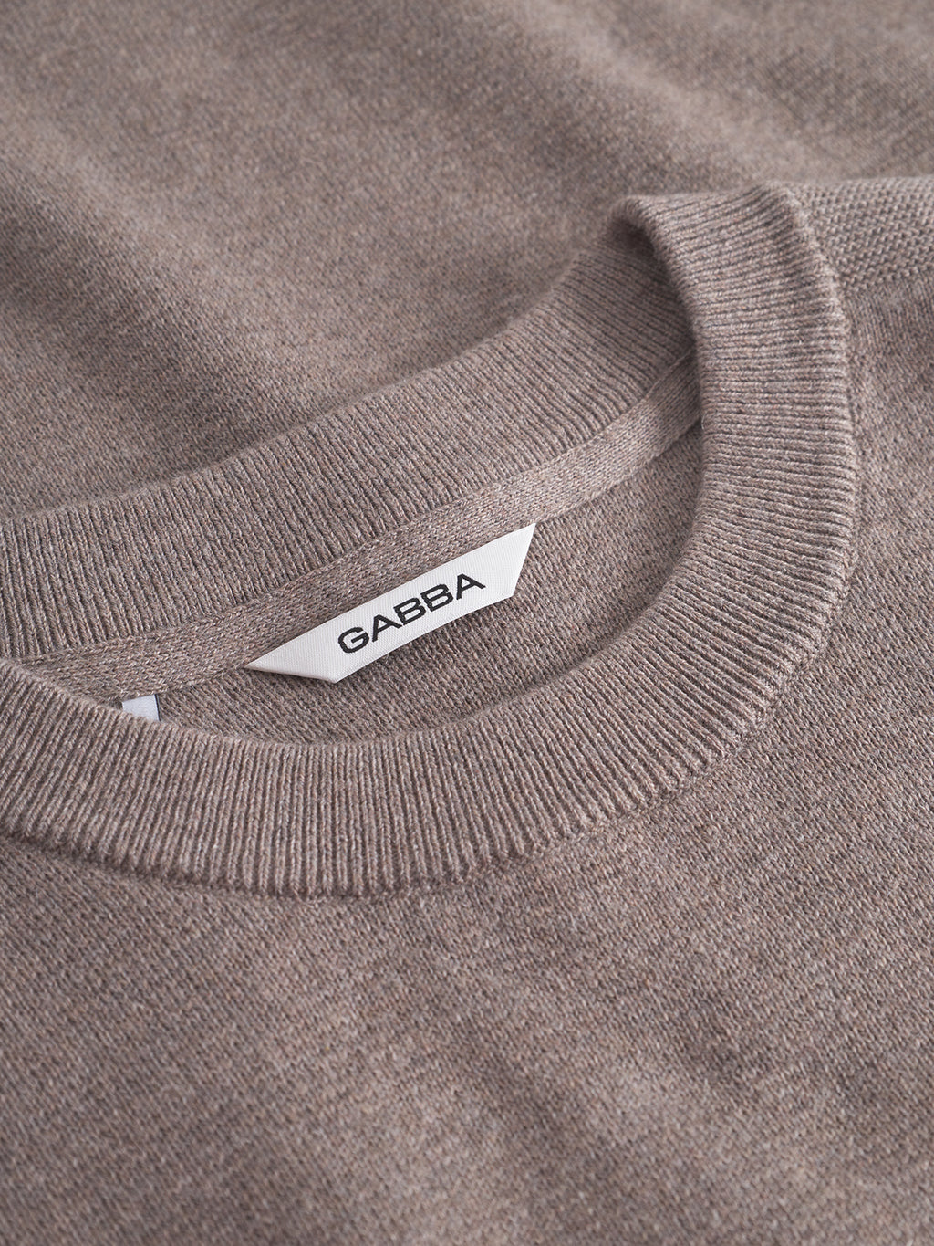 Close-up of the Gabba Blanko New LS sweater in Sand Mel, showcasing its ribbed crew neckline and inner white brand label—perfect for breathable, transitional layering.
