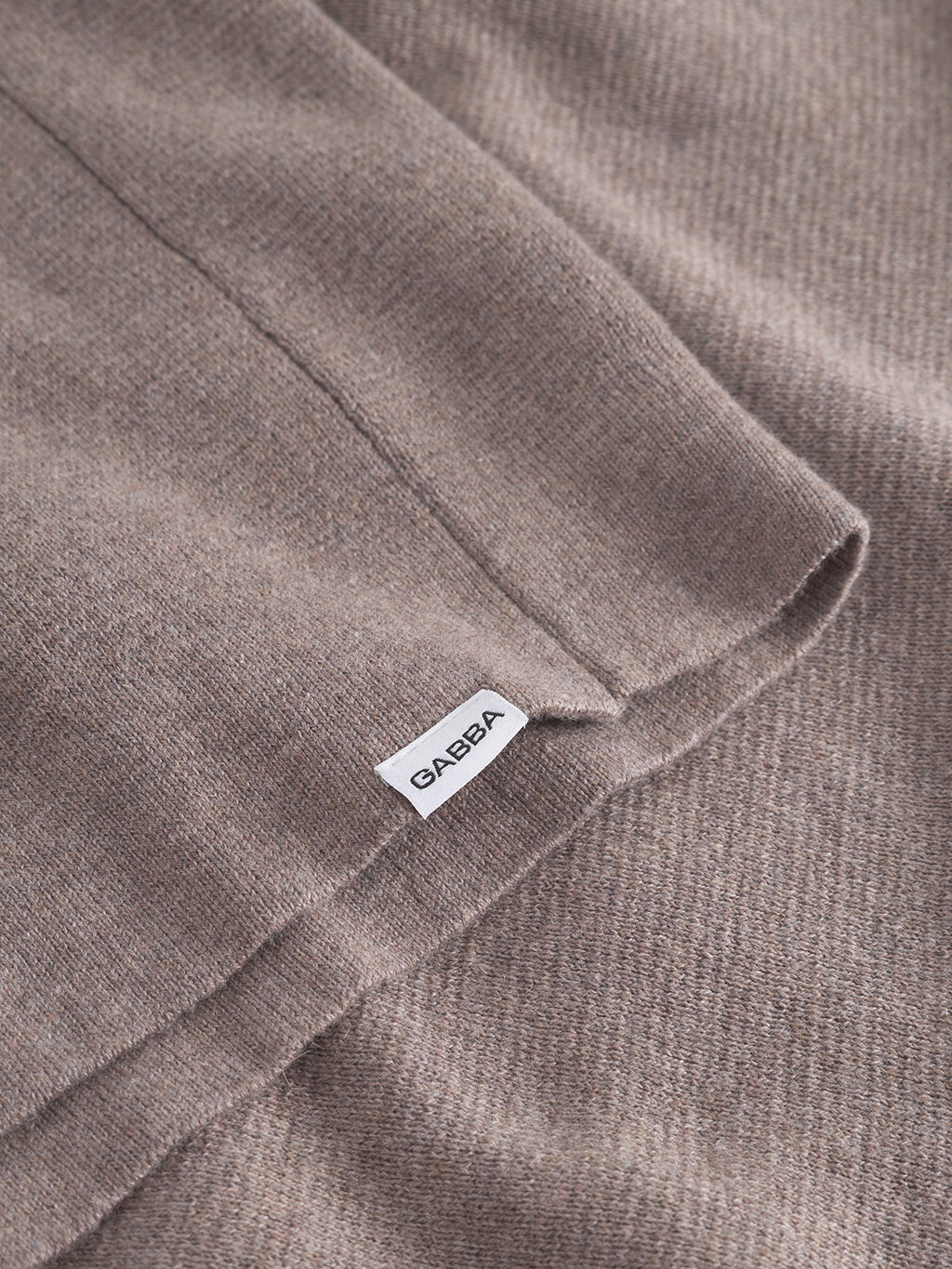 Close-up of the soft, sand melange Milano knit fabric from Gabba's Blanko New LS, featuring a small white GABBA label on the seam. Its breathable texture and cozy, warm feel make it ideal for transitional layering.