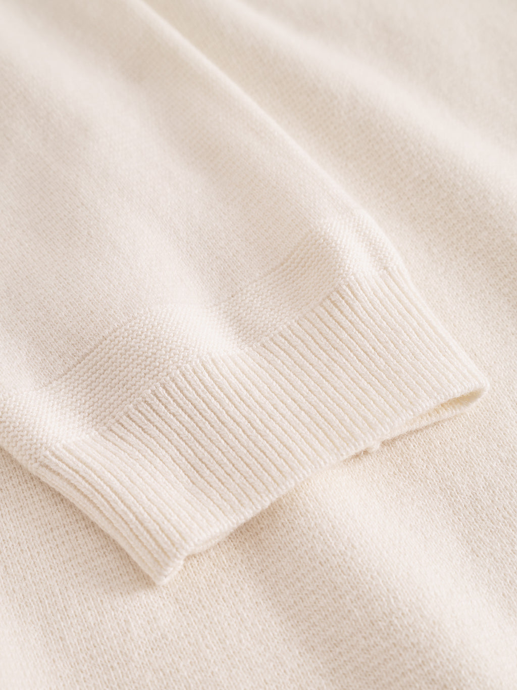 A close-up of the Blanko New Zip LS sweater by Gabba in off white, highlighting the ribbed cuff and soft textured cotton-wool blend fabric.