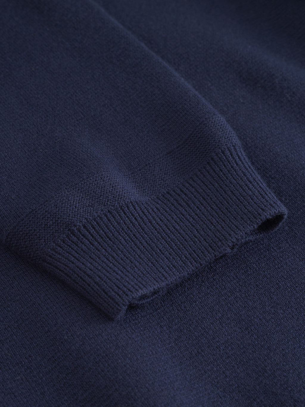 Close-up of Gabba’s Blanko New Zip LS - Navy, a men's half-zip sweater in a cotton-wool blend, highlighting the ribbed cuff against a smooth background.