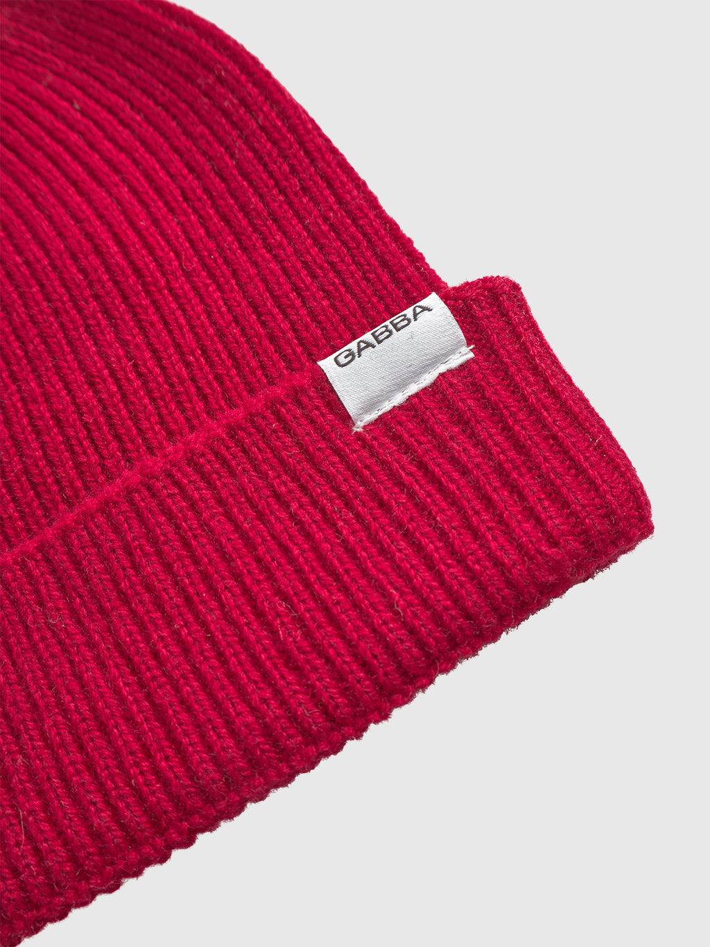 Close-up of the Gabba Biella Aico - Red beanie, featuring a ribbed knit design, folded brim, and a white GABBA tag on the brim, set against a plain white background.