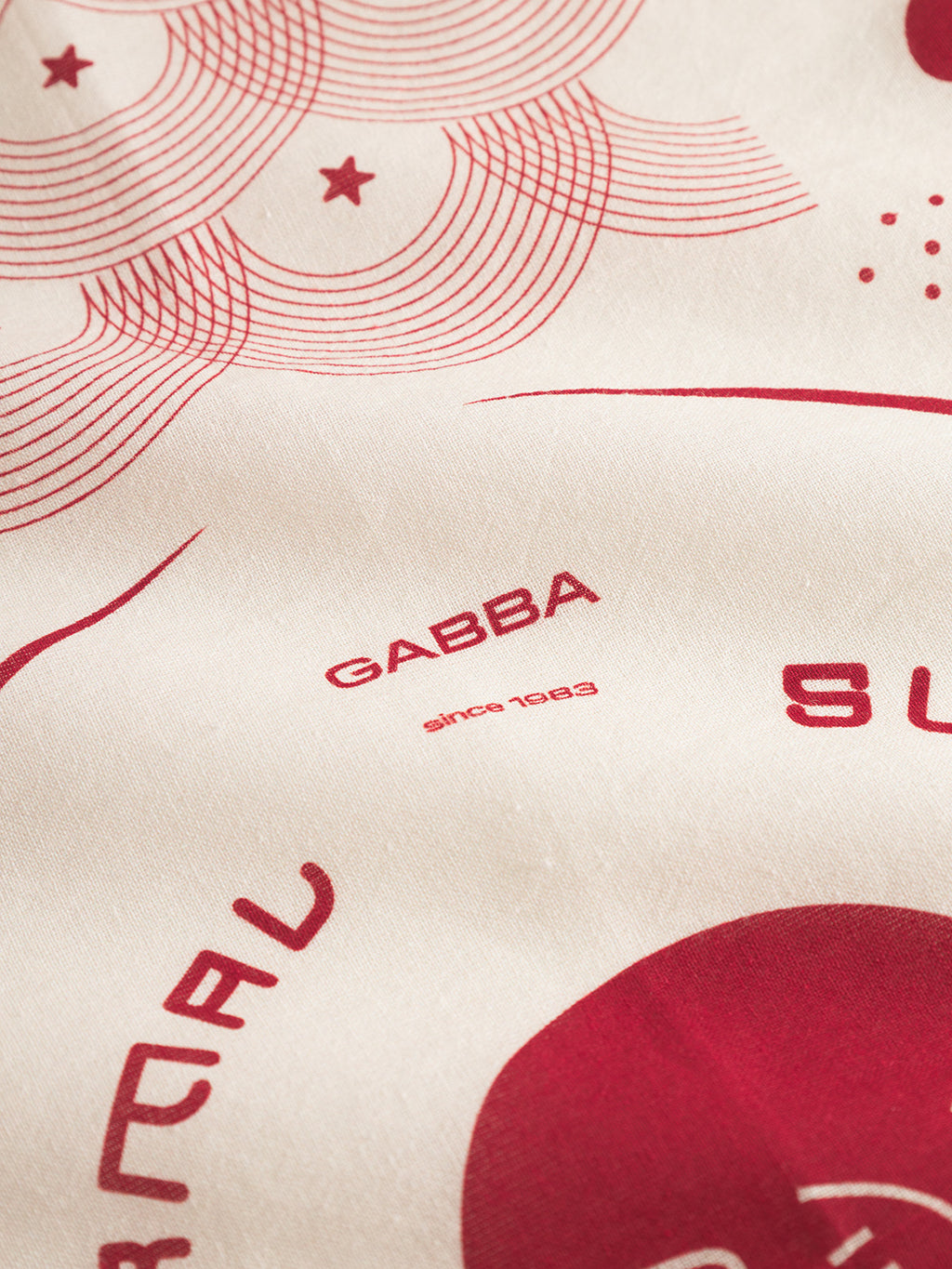 Close-up of the Bandana Waves - Multi Pattern by Gabba, featuring cream cotton fabric with red concentric circles, stars, and dots in a Japan-inspired print. Gabba since 1983 is displayed at the center.