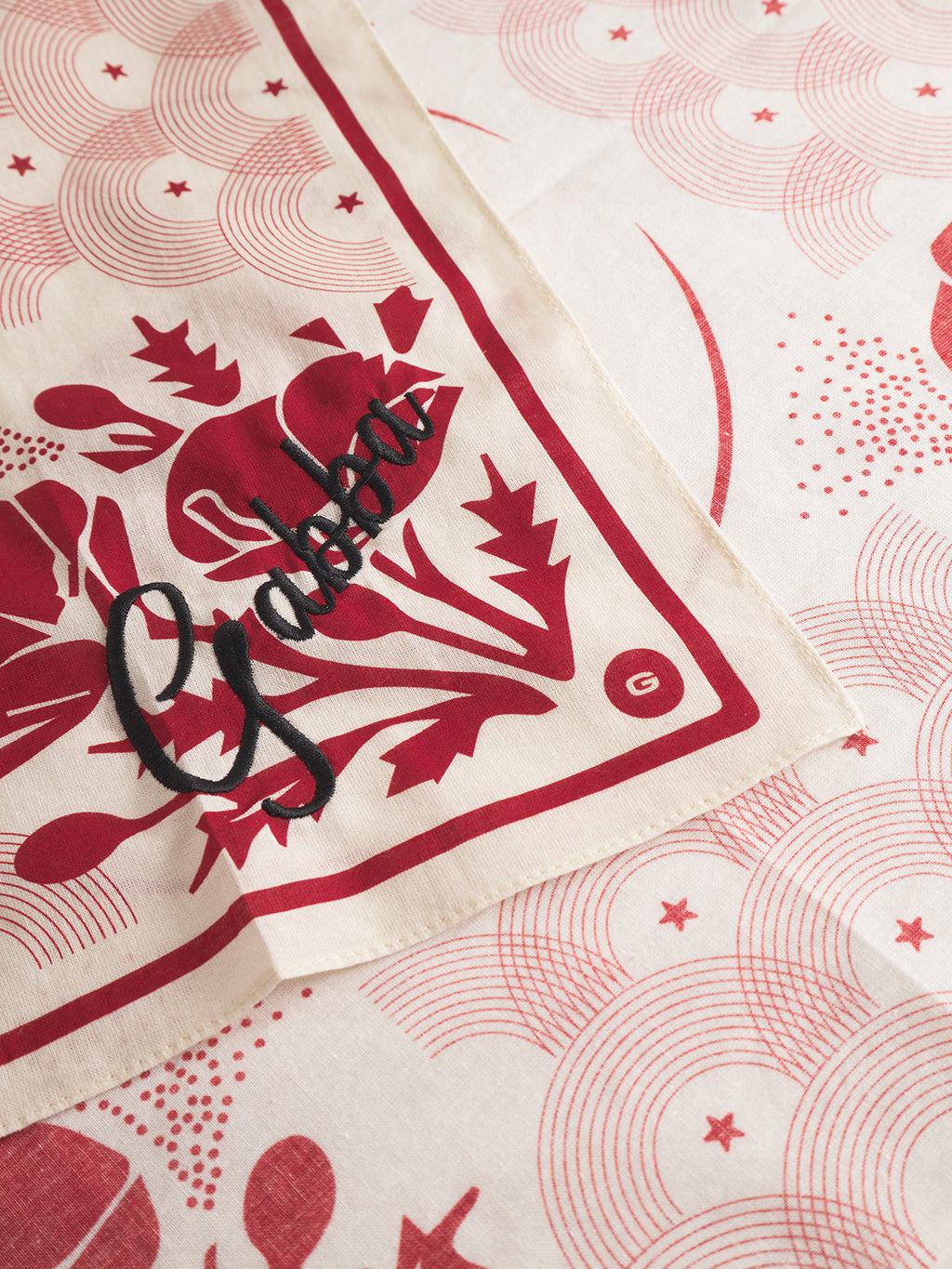 The Gabba Bandana Waves - Multi Pattern features cream cotton with red floral and geometric prints, a bold black Gabba script over red flowers in one corner, plus a small circled G—retro Japan-inspired style.
