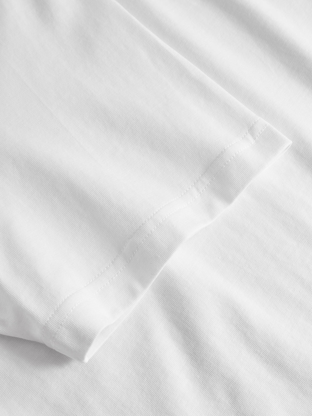 A close-up of the sleeve and hem of Gabbas Dune Kay Dot SS GOTS - White T-shirt, highlighting the organic cotton fabric texture and detailed stitching.