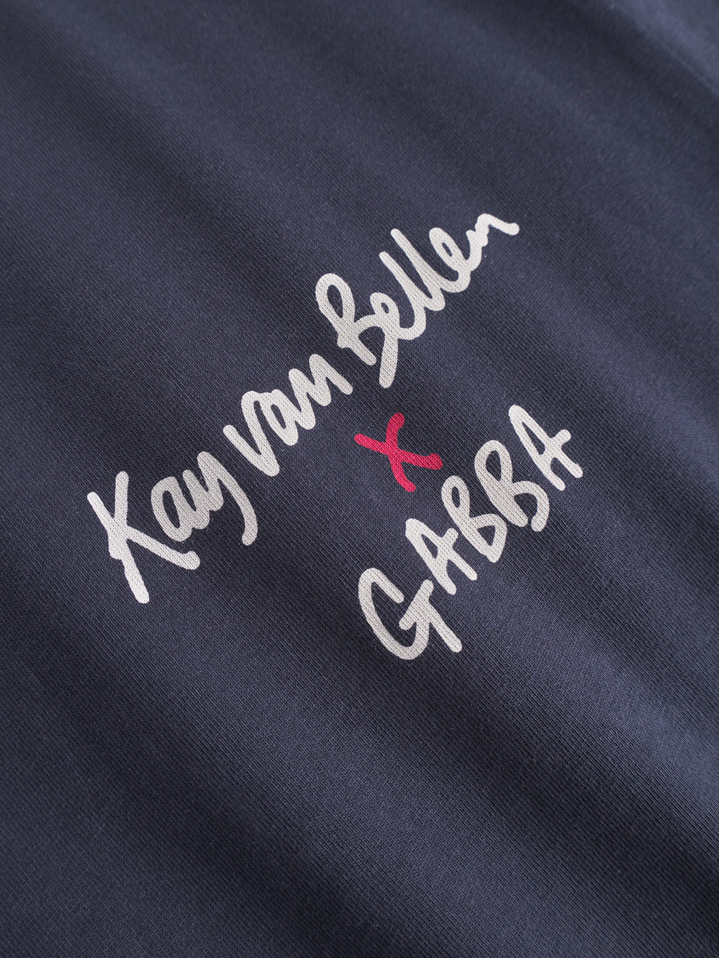 Close-up of the Gabba Dune Kay Man SS GOTS tee in navy organic cotton, with white handwritten Kay van Bellen x Gabba text—red “x” highlights the Japanese-inspired minimalism behind this exclusive collaboration.