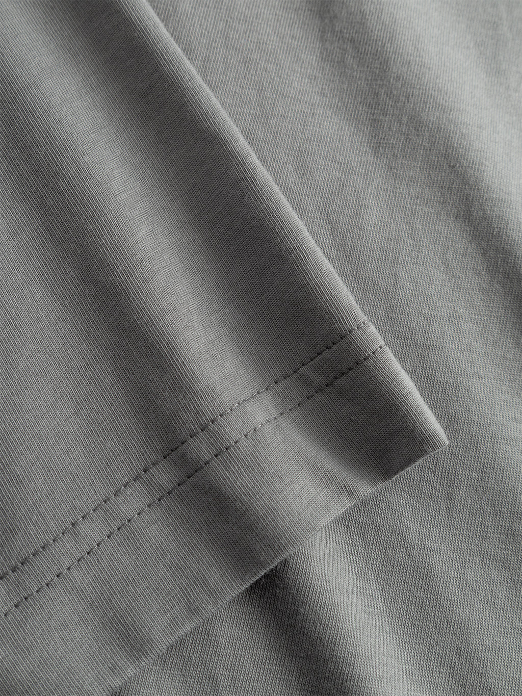 Close-up of the Dune Kay Man SS GOTS T-shirt by Gabba in Dust Sage Green, showing its grey organic cotton sleeve with detailed stitching and fabric texture, highlighting the seam and weave pattern of this GOTS-certified tee.