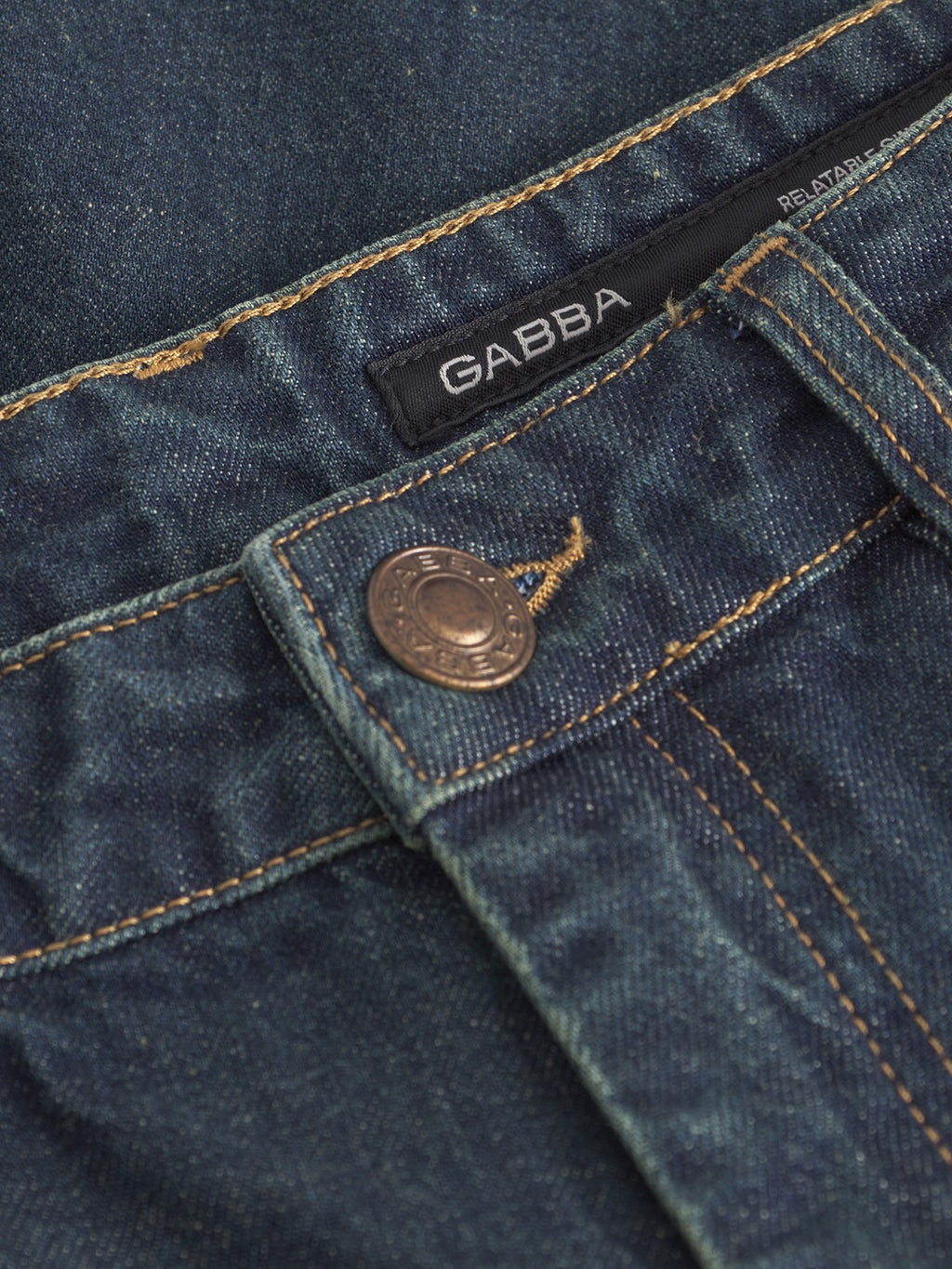 Close-up of Gabba’s Marc Dox straight leg jeans in dark blue denim, showcasing a metal button, orange stitching, and a black brand label—echoing classic vintage workwear style.
