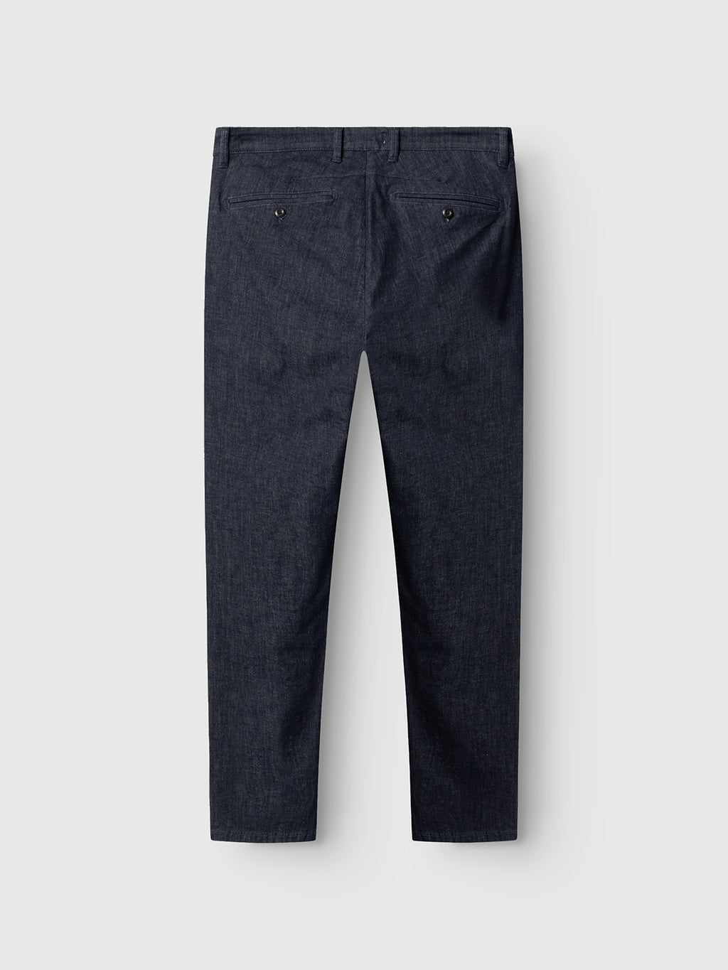 The Paul Sisu - Dark Denim dress pants by Gabba are shown from the back with two buttoned welt pockets and a straight-leg cut, crafted from dark navy blue stretch denim, displayed against a light gray background.