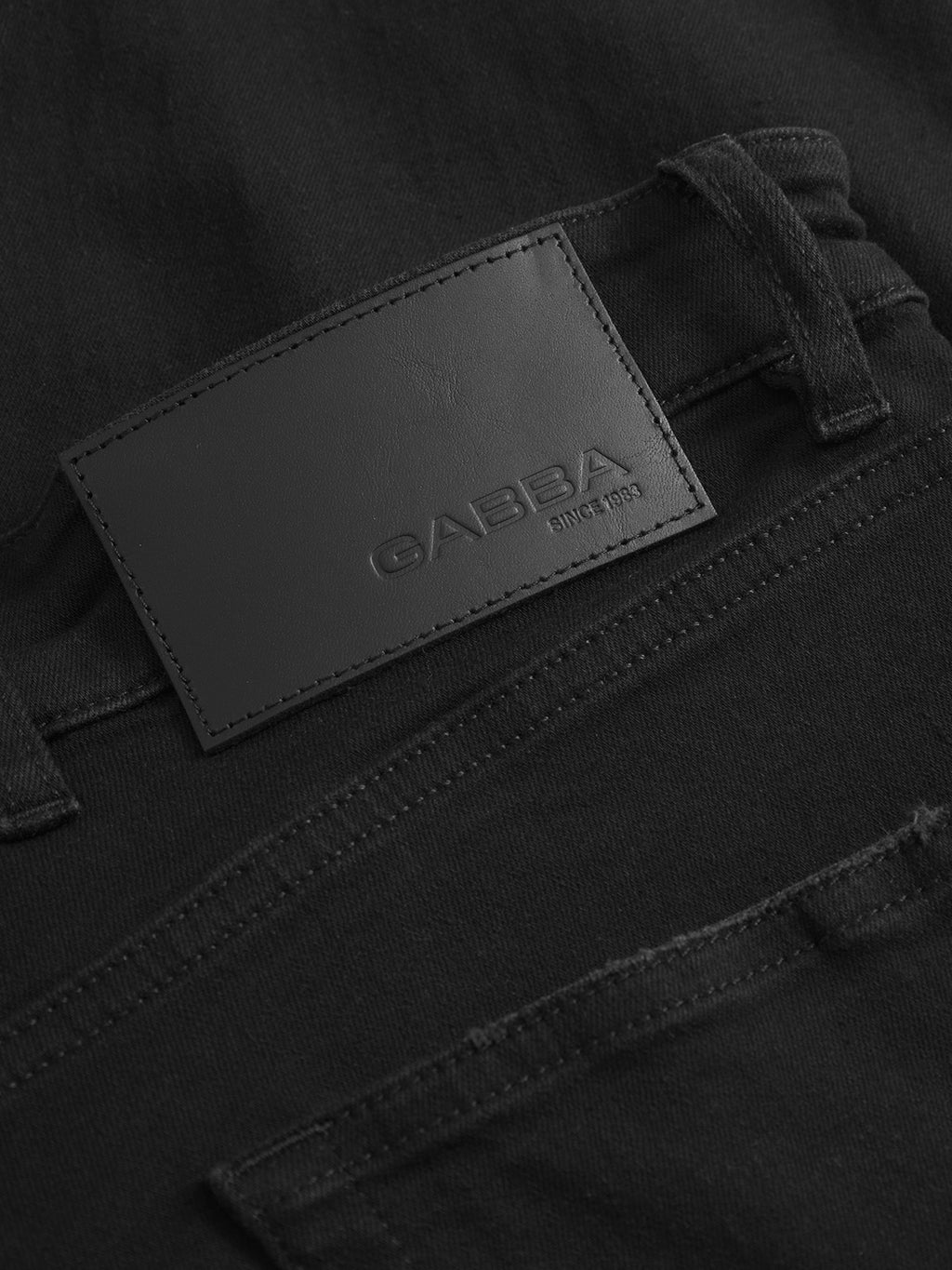 Close-up of the back pocket and waistband of Alex Dusa - Black Denim jeans by Gabba, showing a black leather patch with the embossed Gabba brand name and SINCE 1983 text.