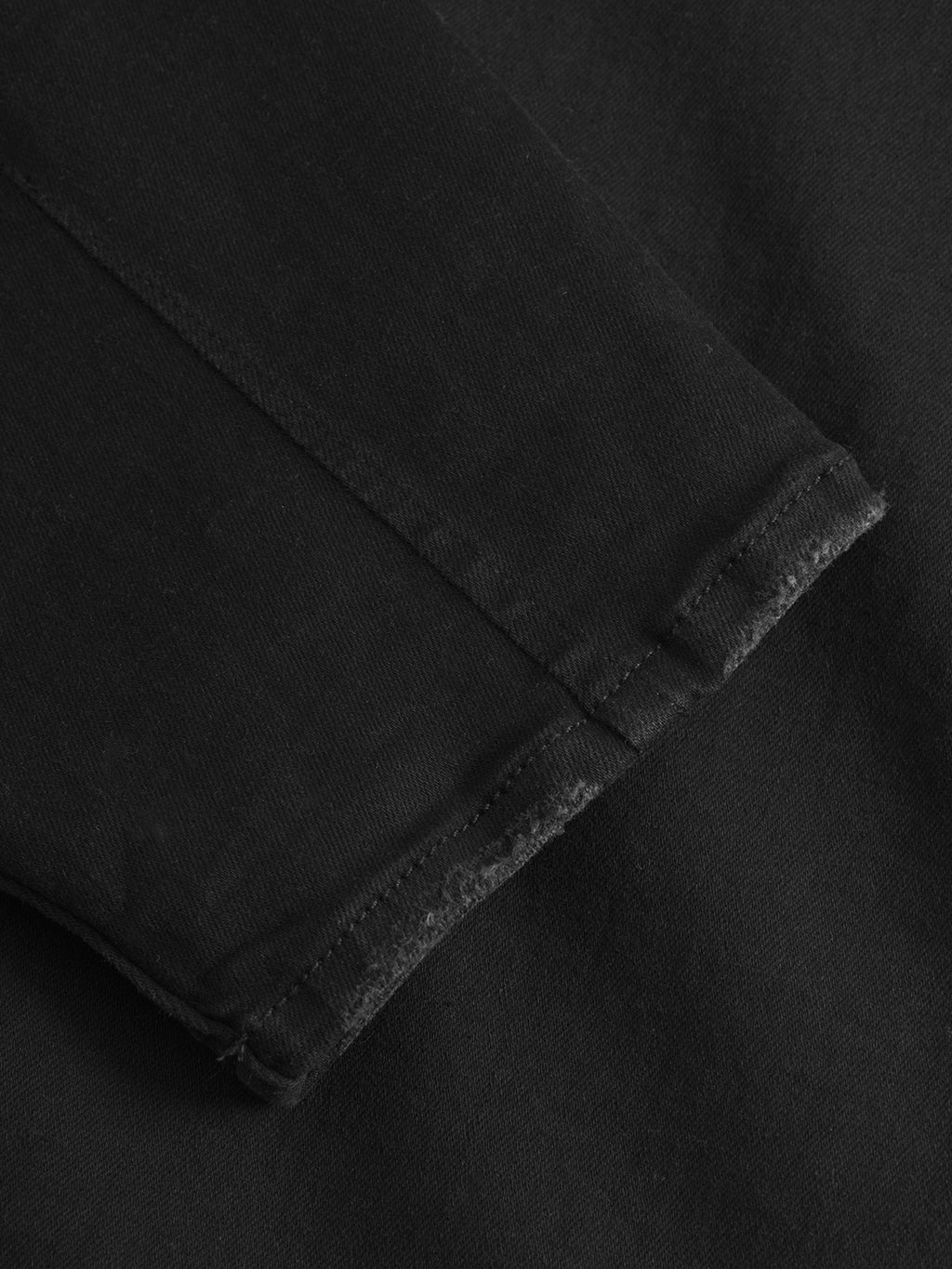 Close-up of the cuff on the Gabba Alex Dusa black denim long-sleeve, showing visible stitching and subtly worn edges, set against a dark background.