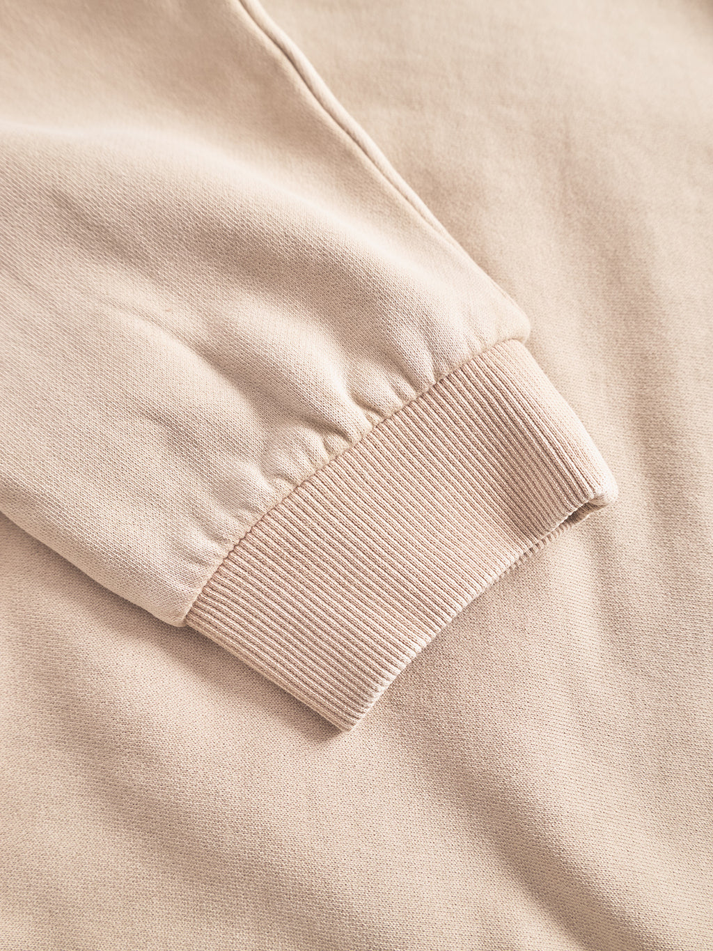 Close-up of the Gabba Delphi Bump GWC sweatshirt in Sand, featuring a ribbed cuff—laid flat on matching fabric background, ideal for casual layering with your favorite soft jersey hoodie.