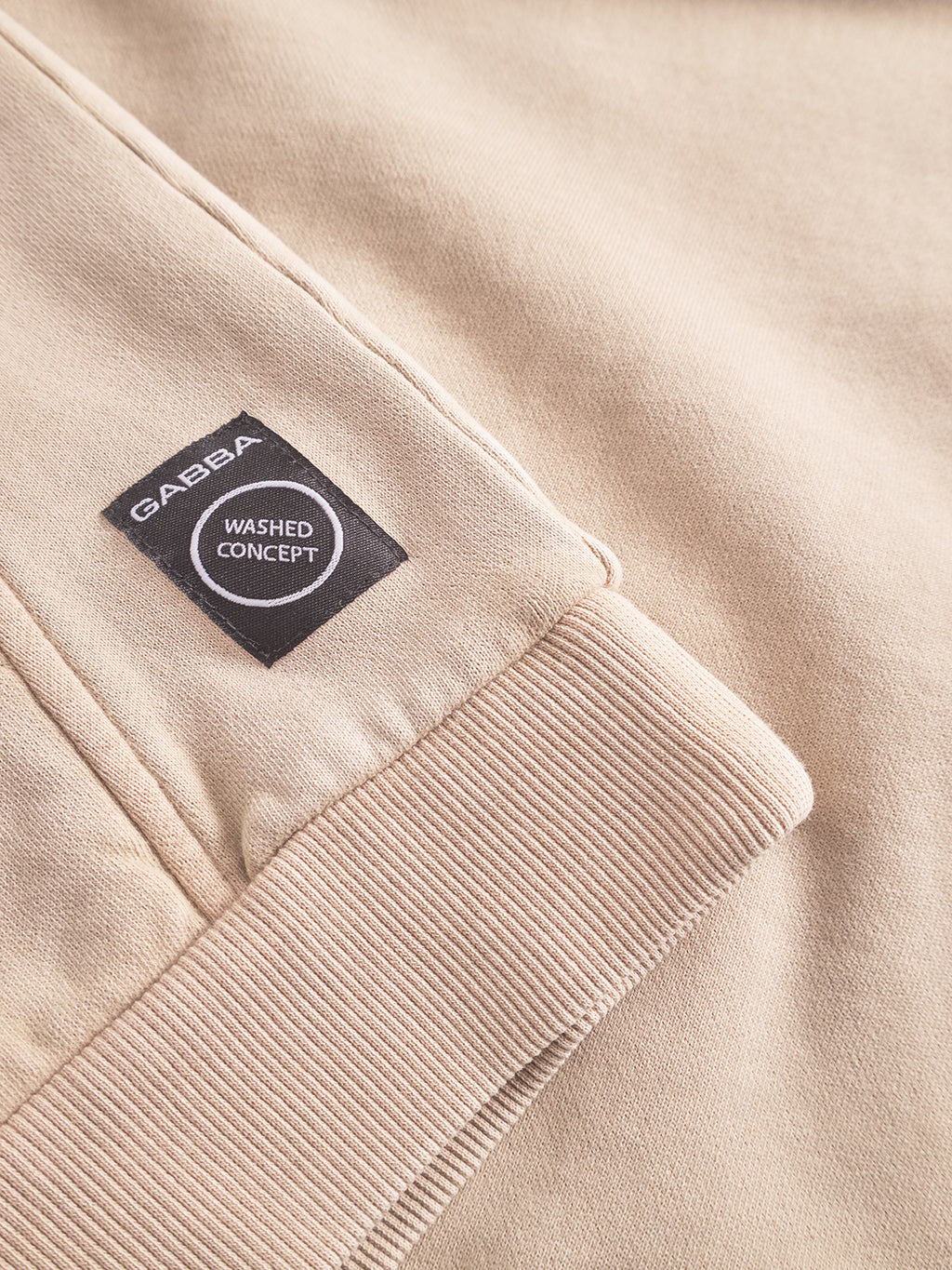Close-up of the Gabba Delphi Bump GWC - Sand sweatshirt featuring a ribbed cuff and a black GABBA WASHED CONCEPT label stitched near the cuff, ideal for casual layering.