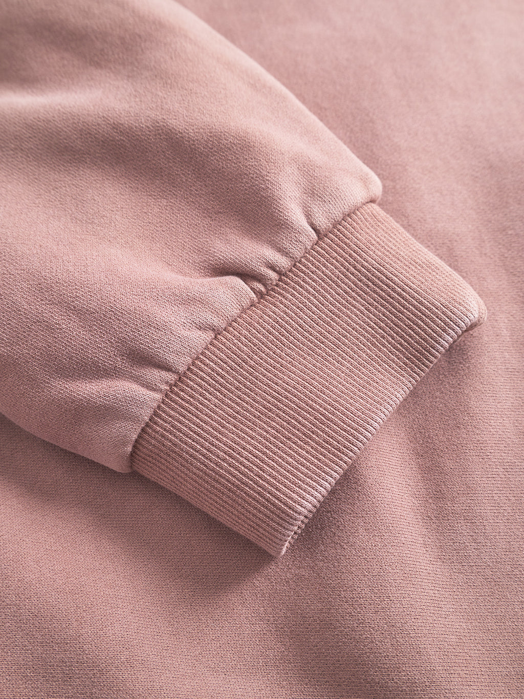 Close-up of the Gabba Delphi Bump GWC - Rose sleeve with ribbed cuff, highlighting texture and fabric details. The light pink sweatshirt is laid flat on a matching background for a modern, casual look.