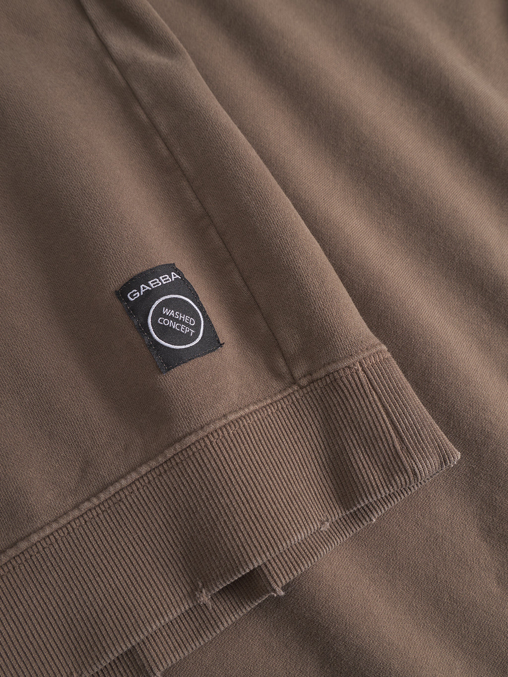 Close-up of the Gabba Volos Bump GWC sweatshirt in brown, featuring a crew neck, ribbed hem, super-soft textured fabric, and a small black label reading GABBA WASHED CONCEPT.